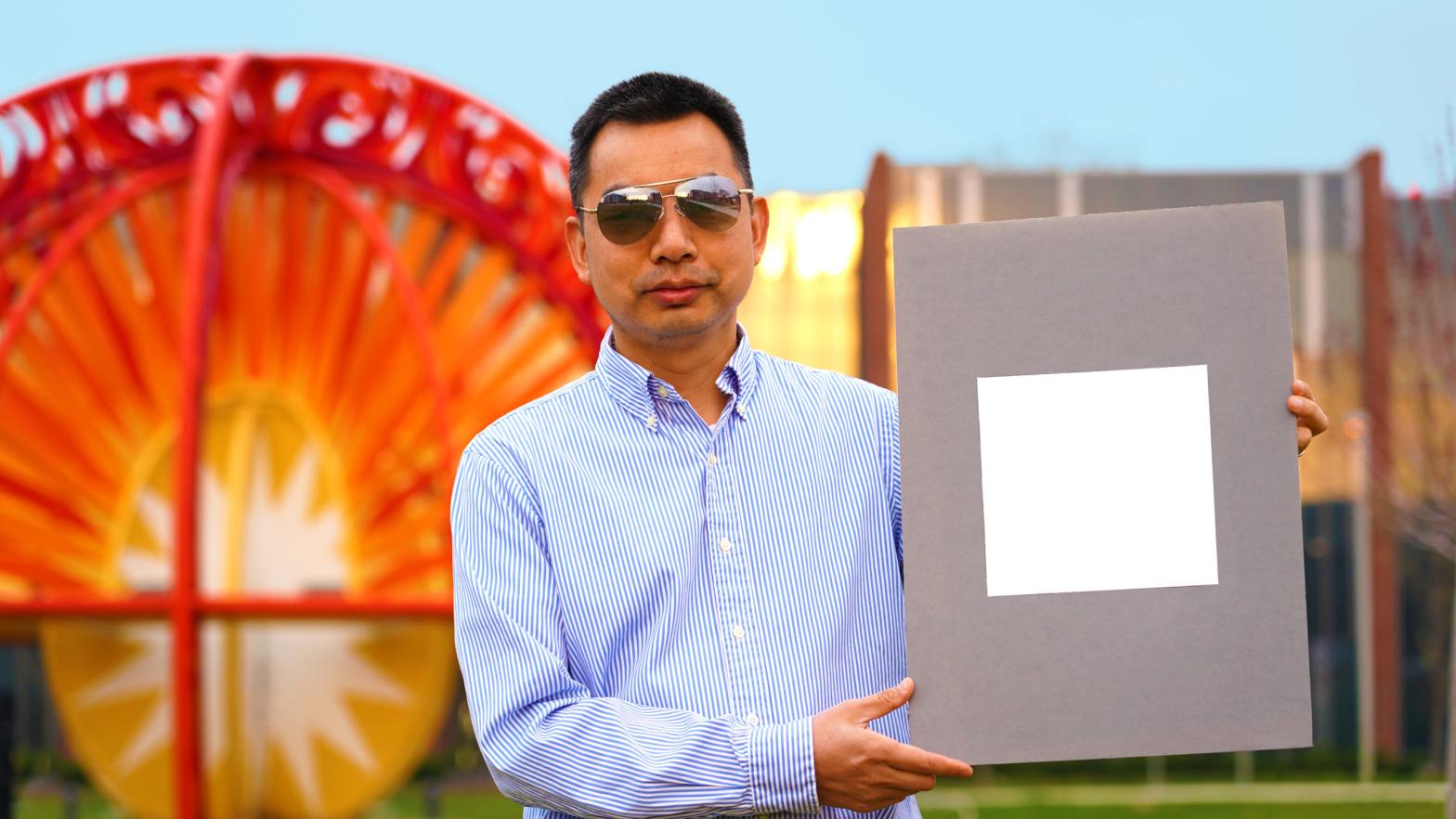 Xiulin Ruan holds up his lab's sample of the whitest paint on record. That's some white paint! (Photo: Purdue University/Jared Pike)