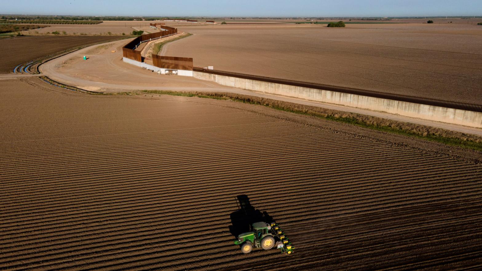 The border wall construction is seen near farmland as a tractor plows a field in Progreso, Texas (Photo: Julio Cortez, AP)