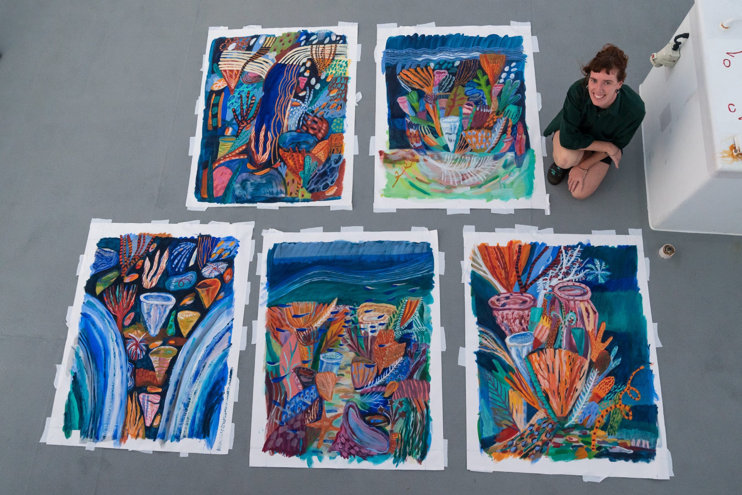 Ellie Hannon on the research vessel with the paintings she made onboard (Photo: Schmidt Ocean Institute)