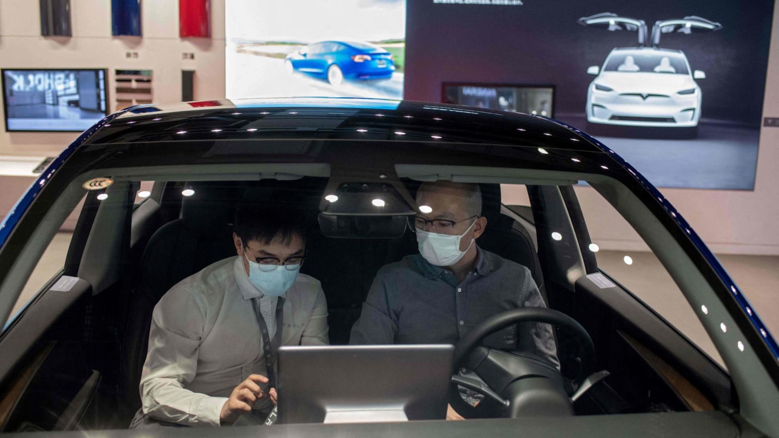 A man sits inside of a Tesla car Model 3 as a vendor talks to him at a Tesla shop inside of a shopping mall in Beijing on May 26, 2021.  (Photo: Nicolas Asfouri/AFP, Getty Images)