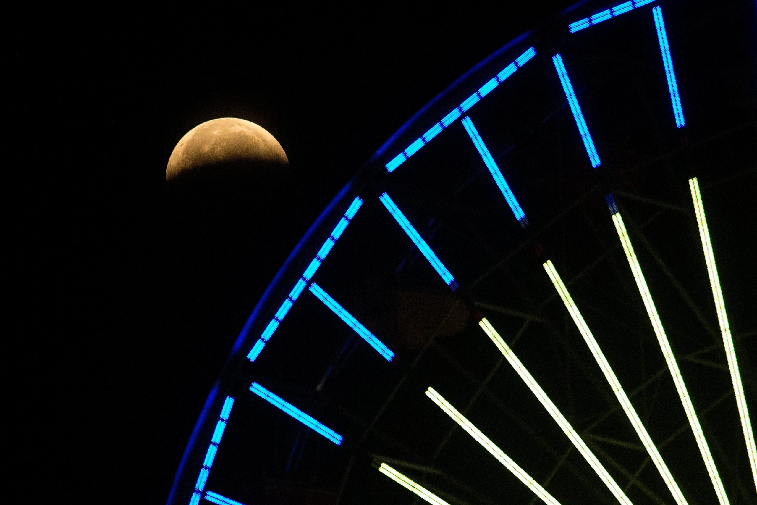 The lunar eclipse progresses is seen behind a ferris wheel over Santa  Monica Beach in Santa Monica, Calif., Wednesday, May 26, 2021. (Photo: Ringo H.W. Chiu, AP)