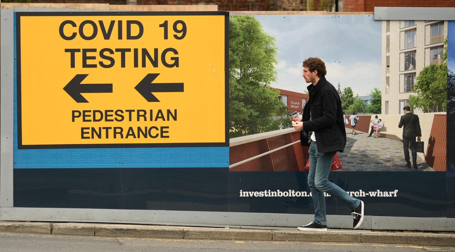A pedestrian walks past a sign directing members of the public to a covid-19 testing centre in Bolton, England, on May 28, 2021.  (Photo: Oli Scarff/AFP, Getty Images)