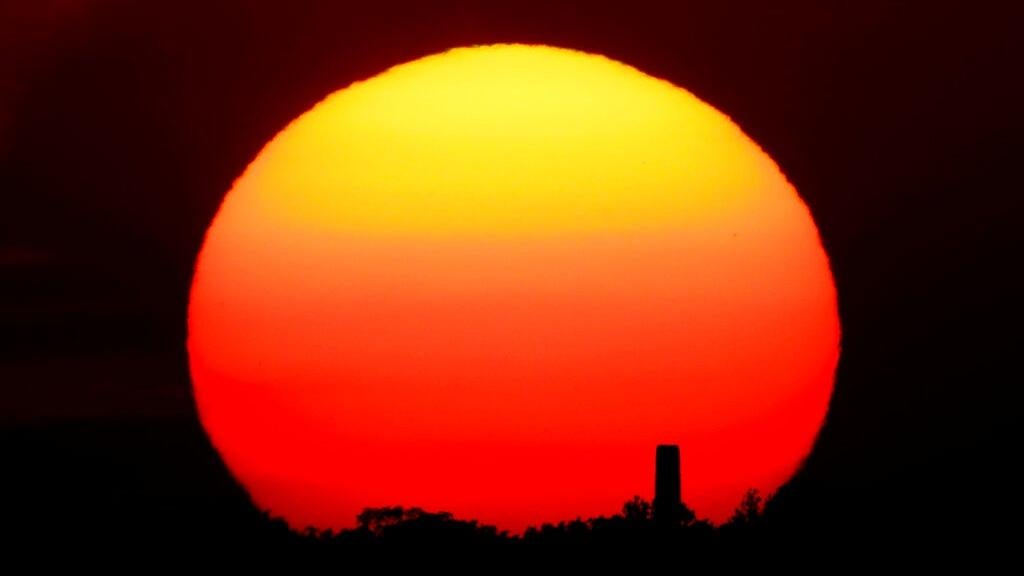 The sun sets behind a smokestack in Kansas City. (Photo: Charlie Riedel, AP)