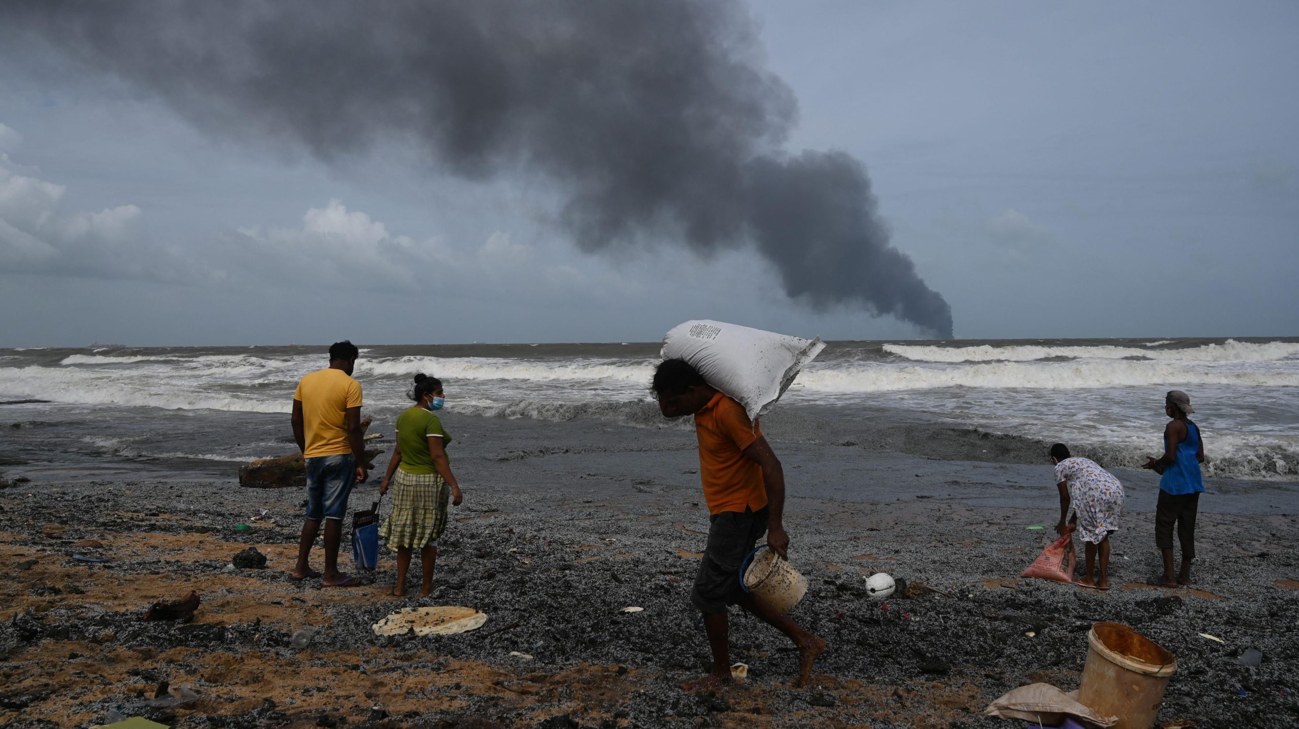 Residents collect debris from the burning ship on May 26. (Photo: Lakruwan Wanniarachchi/ AFP, Getty Images)