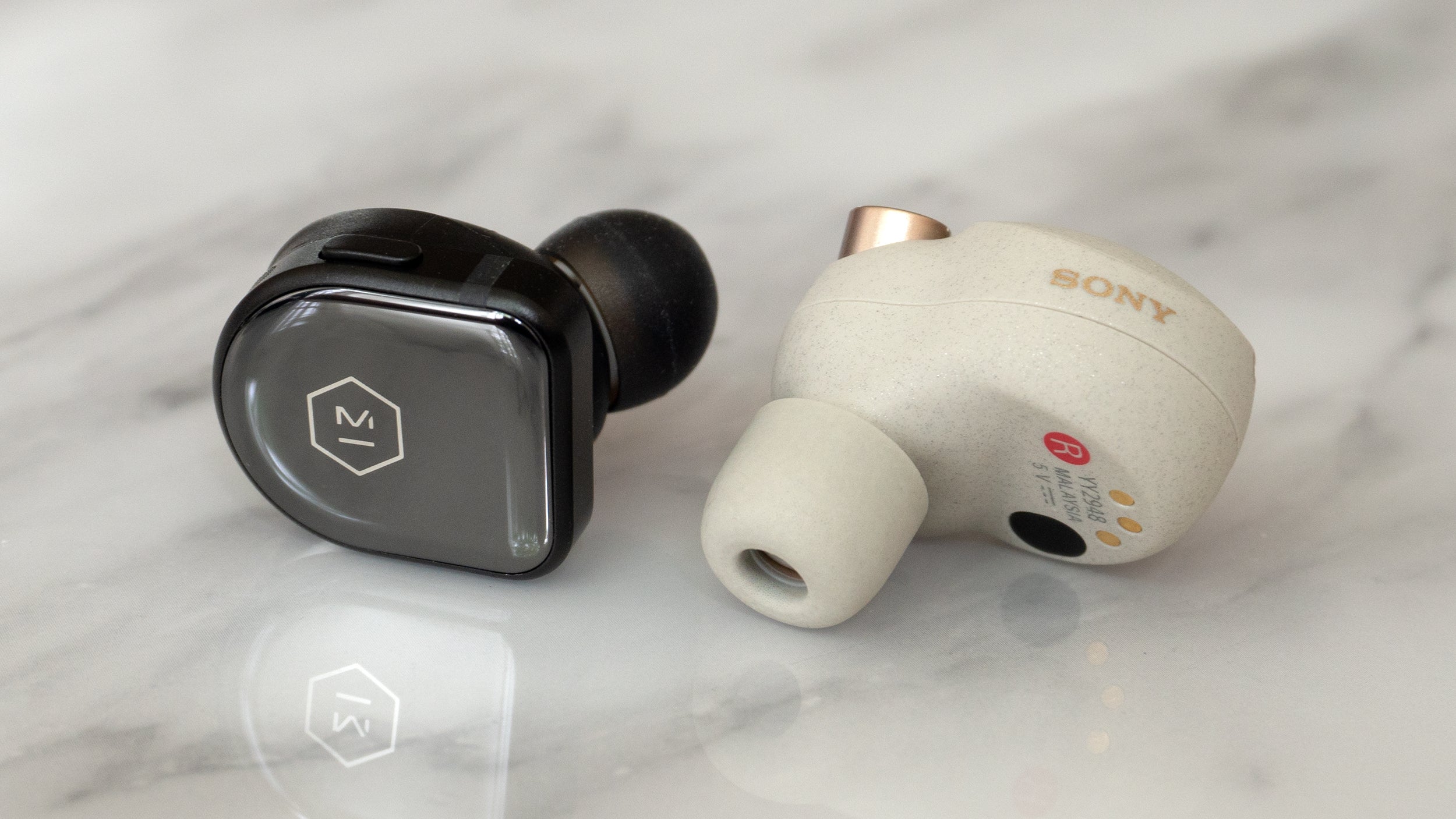 Despite being smaller, the Master & Dynamic MW08 wireless earbuds (left) include 11mm drivers, compared to the 6mm drivers in the larger Sony WF-1000XM3 earbuds (right). (Photo: Andrew Liszewski/Gizmodo)