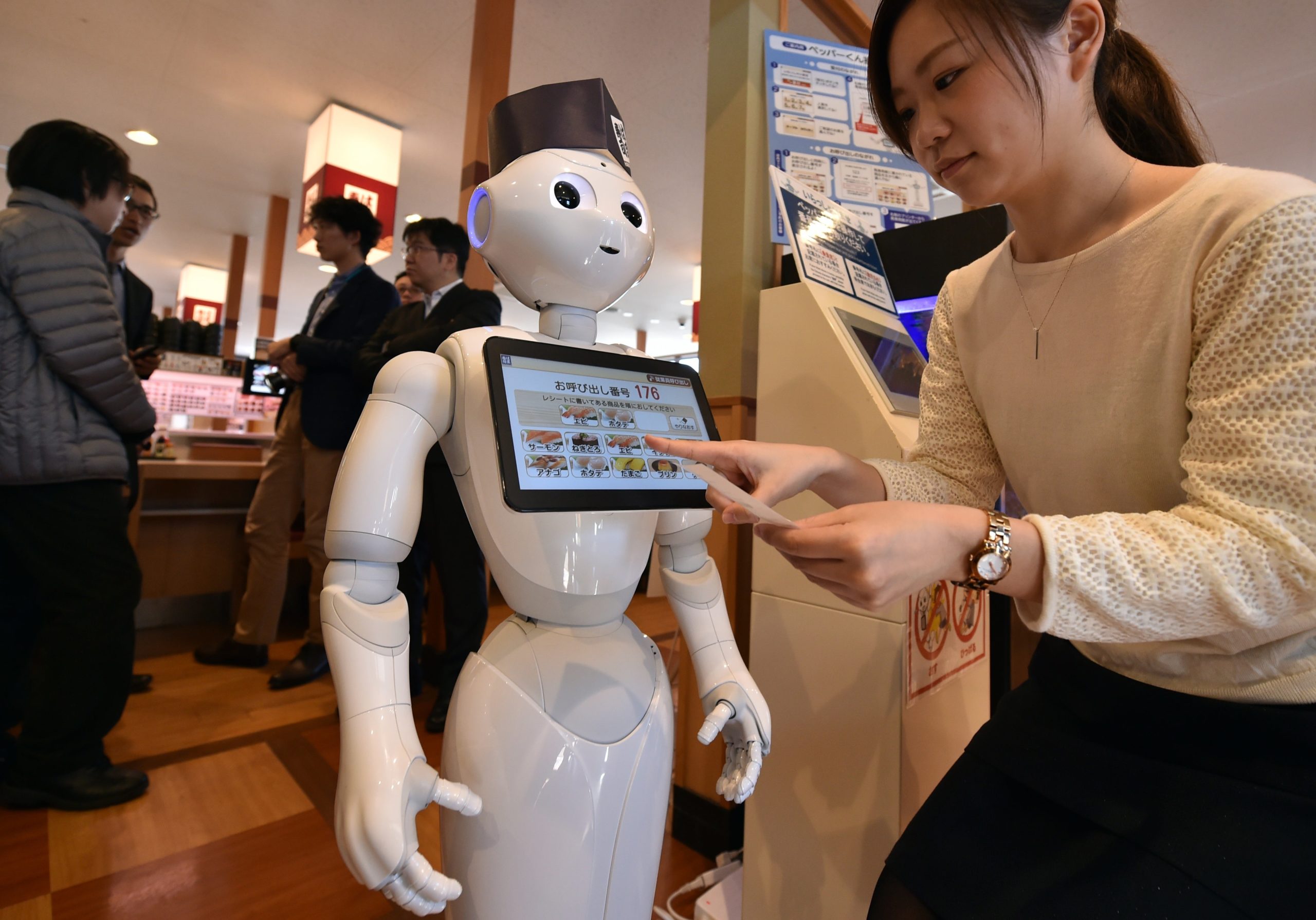 An employee of sushi restaurant Hamazushi interacts with Pepper during a press preview in Saitama, Japan on February 2, 2017. (Photo: Kazuhiro Nogi/AFP, Getty Images)