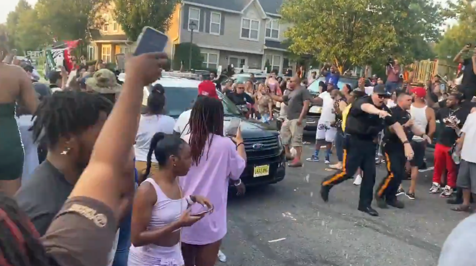 Officers clear a path for a police vehicle containing Edward Cagney  Mathews, under arrest on charges of bias intimidation and trespassing, after protesters surrounded his residence on July 5. (Screenshot: Danny Freeman / NBC Philadelphia / Twitter, Fair Use)