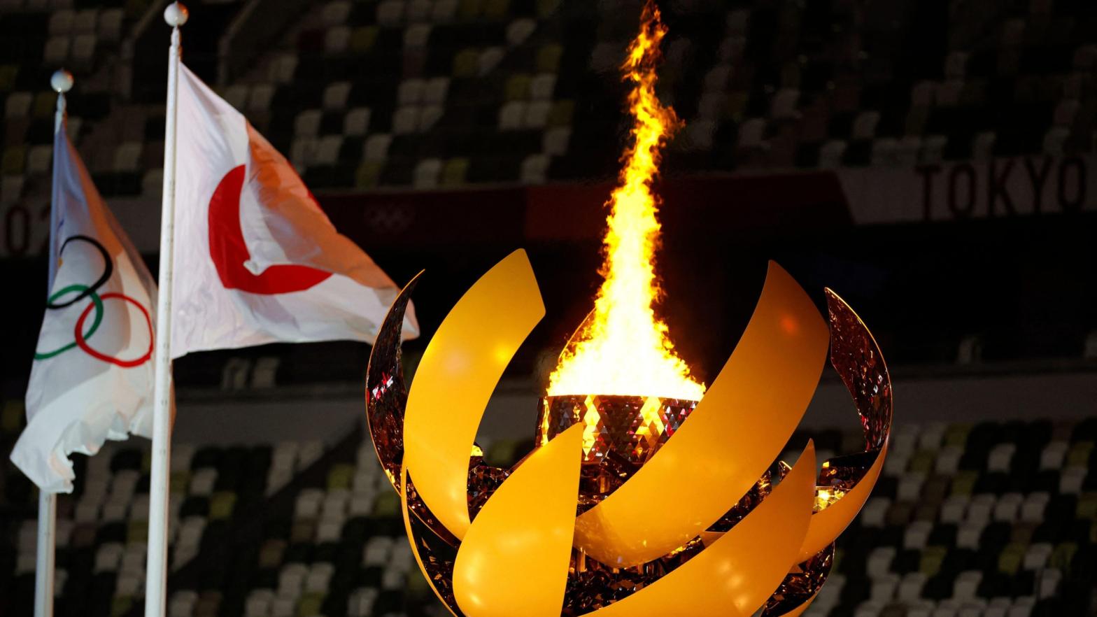 A picture shows the Olympic Flame and Cauldron next to the Japanese and Olympic flags during the opening ceremony of the Tokyo 2020 Olympic Games, (Photo: Odd Andersen / AFP, Getty Images)