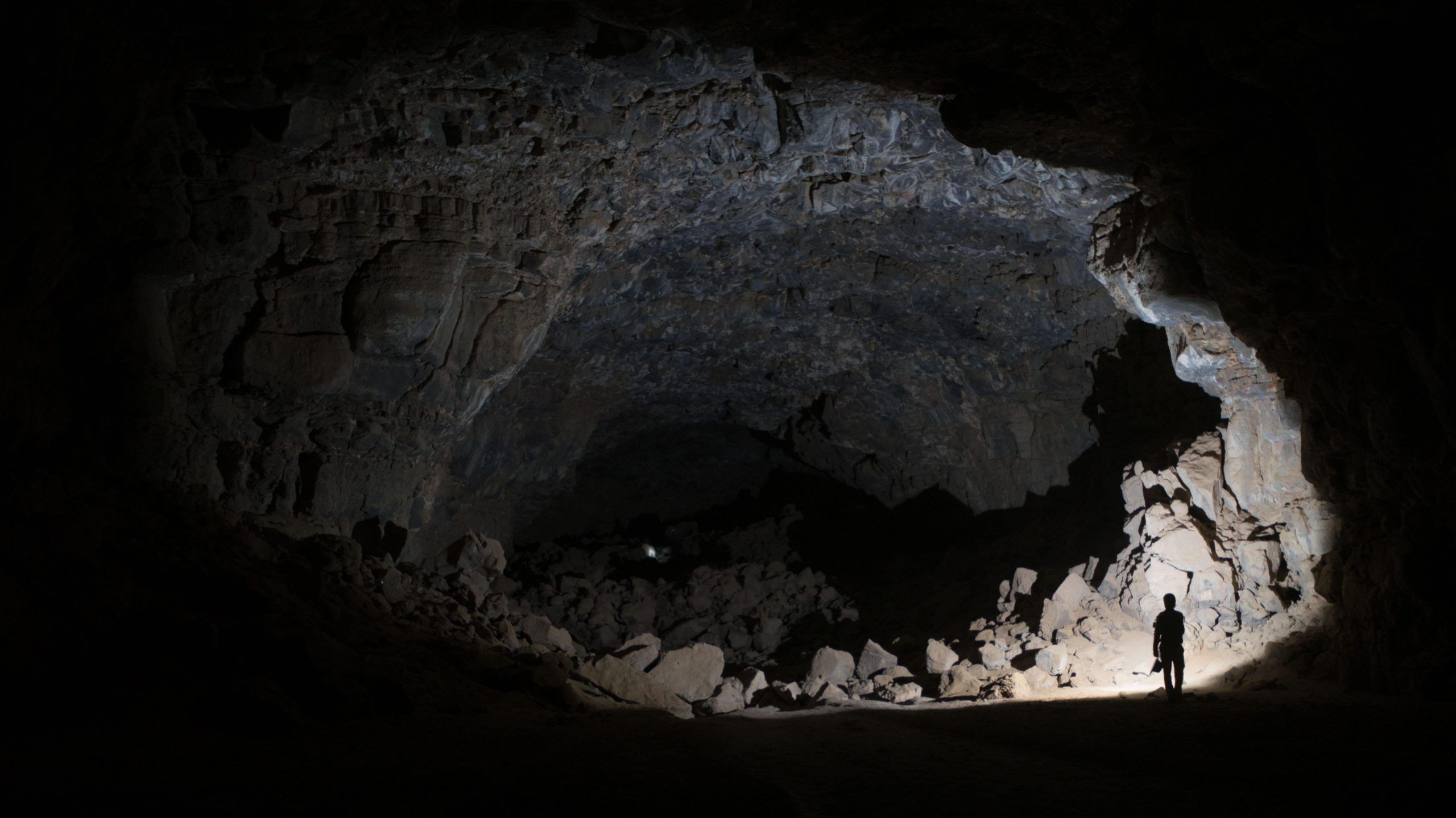 The a cavernous opening in the Umm Jirsan lava tube, illuminated by a researcher's light. (Image: THE PALAEODESERTS PROJECT)