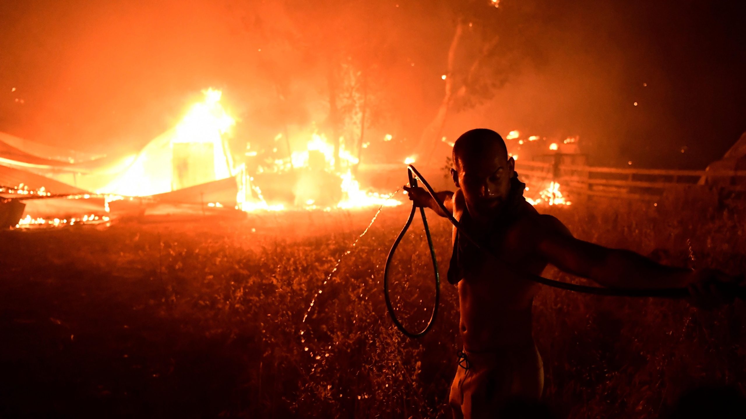 A man uses a water hose during a wildfire in Adames area. (Photo: Michael Varaklas, AP)