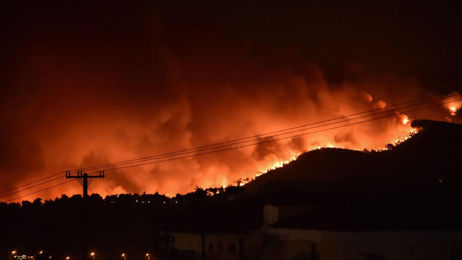Flames rise from a fire spreading around Kapandriti, a town on the outskirts of Athens, Greece, on August 5, 2021. (Photo: Louisa Gouliamaki, Getty Images)