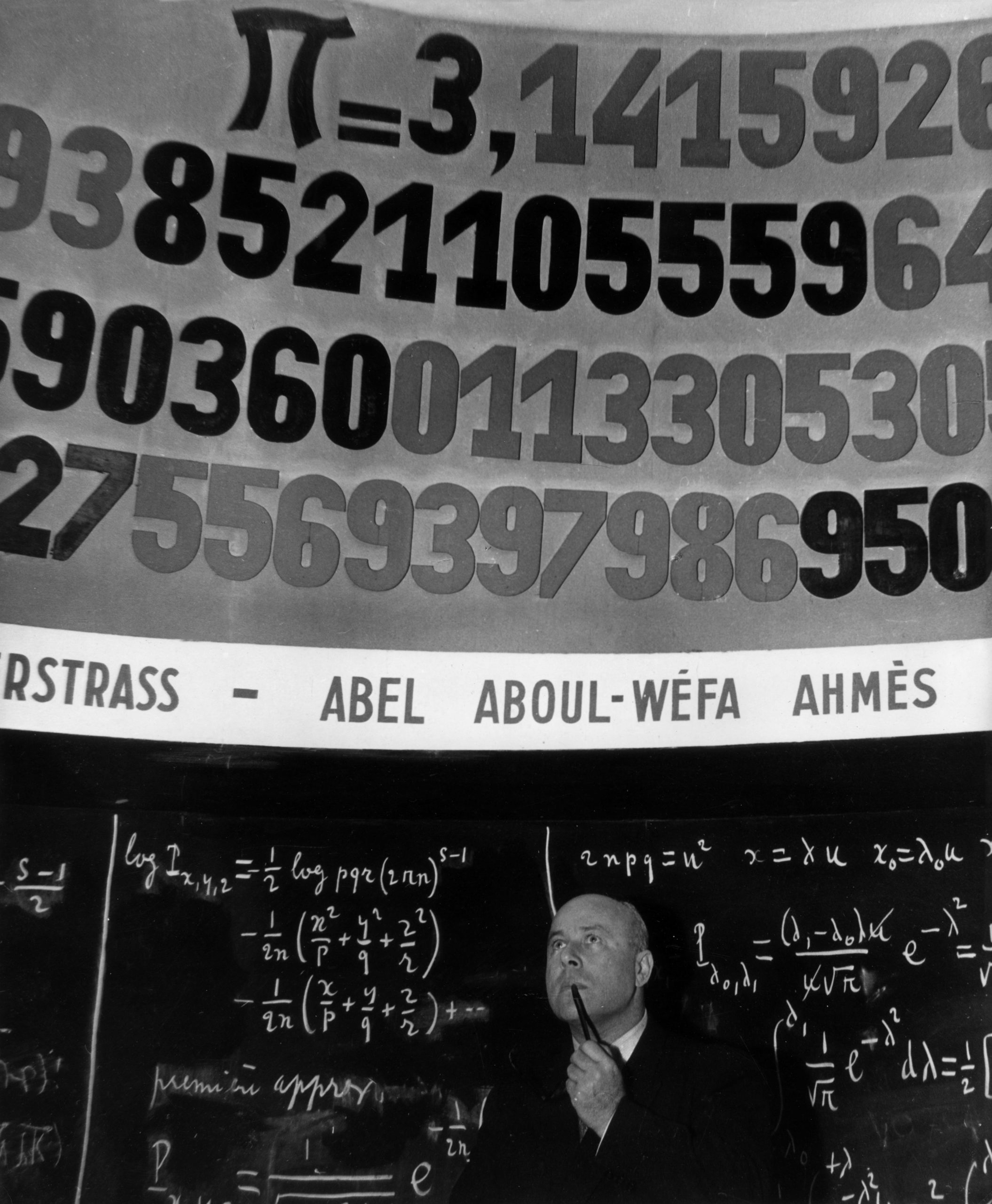 A man  in front of a board showing pi in the 1960s. (Image: Paul Almasy/BIPs, Getty Images)