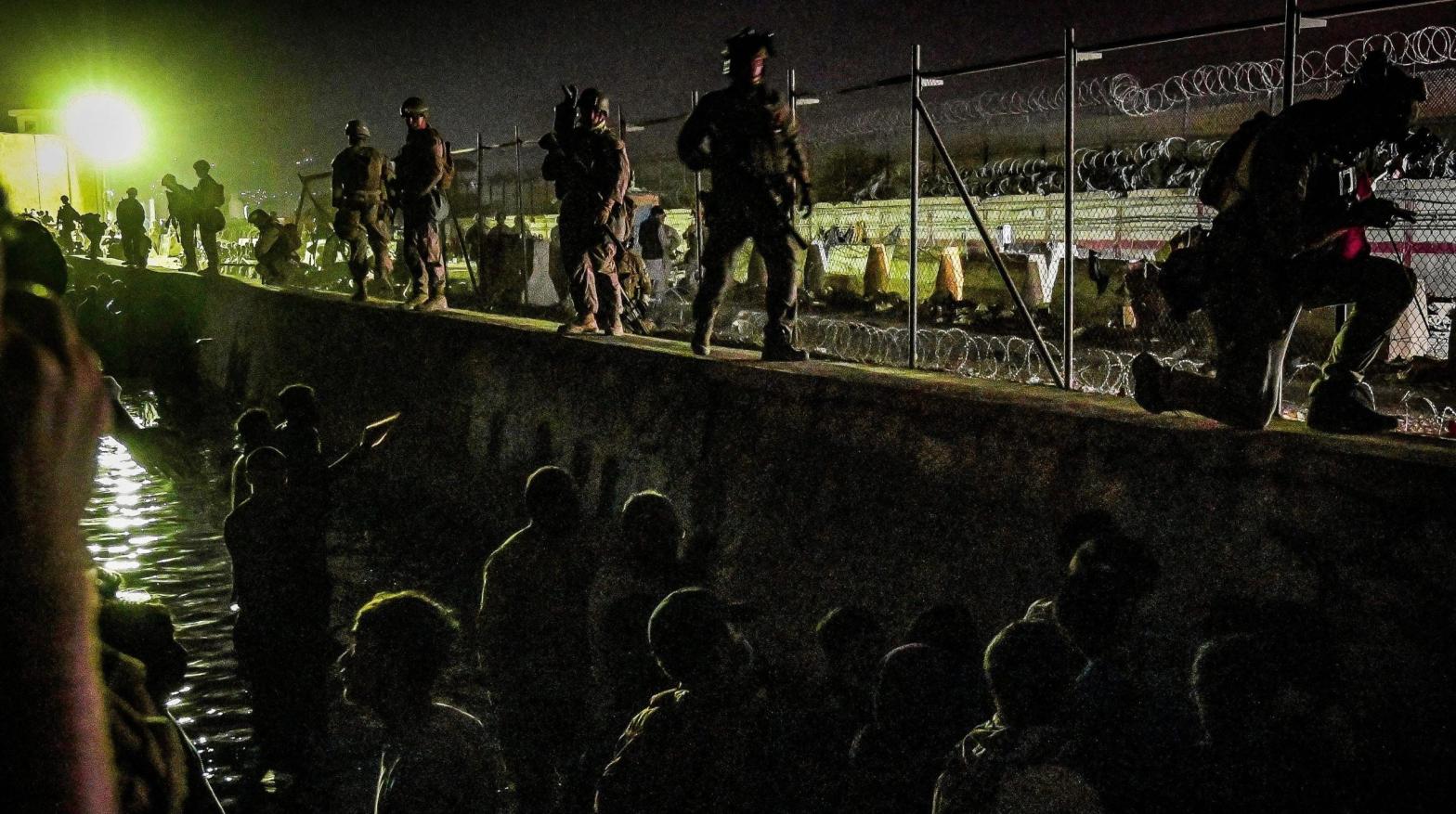 British and Canadian soldiers stand guard near a canal as Afghans wait outside the foreign military-controlled part of the airport in Kabul on August 22, 2021. (Photo: Wakil Kohsar/AFP, Getty Images)