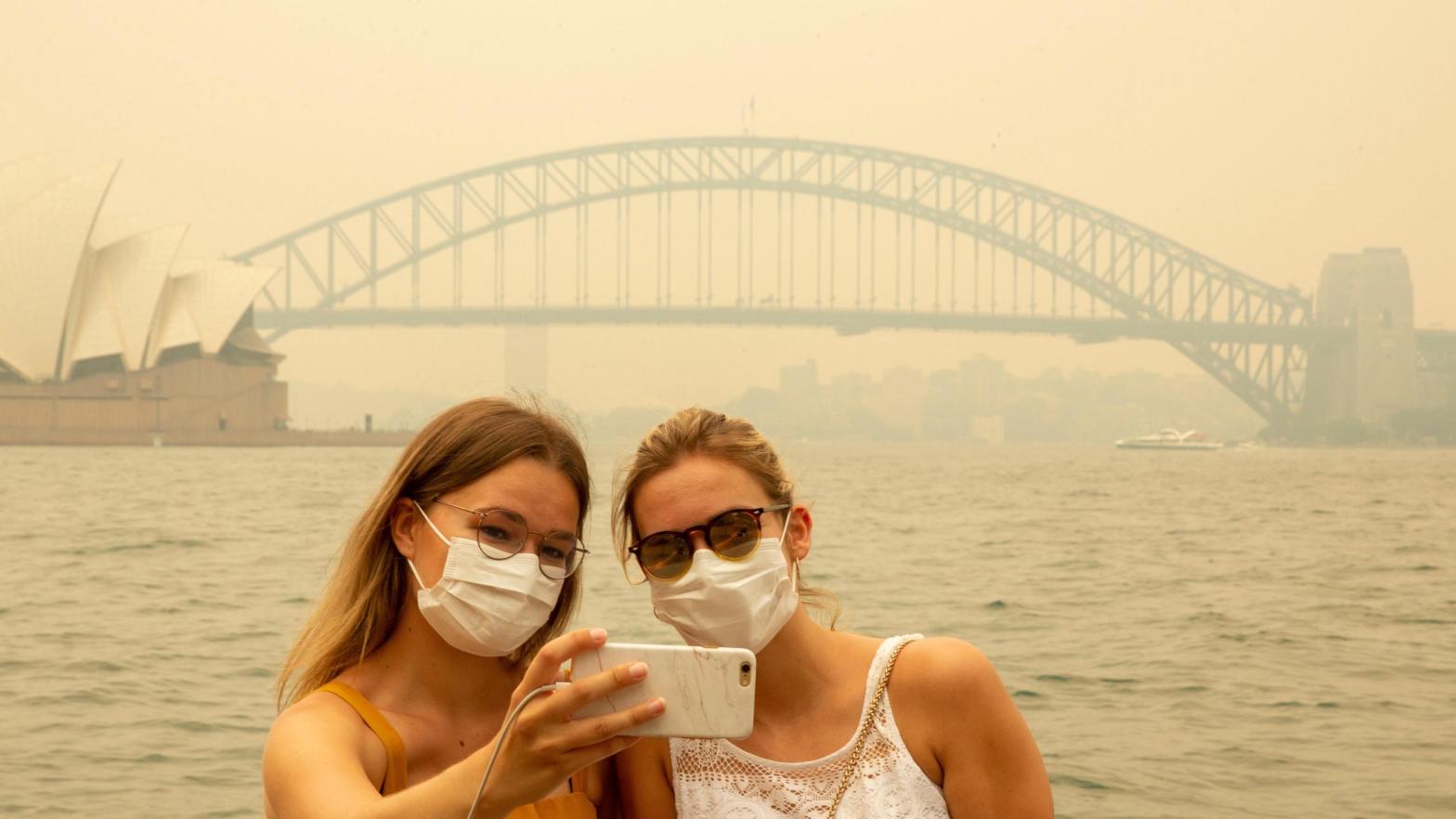 Tourists take a selfie while wearing face masks due to heavy smoke (this is pre-pandemic!) on Dec. 19, 2019 in Sydney, Australia. (Photo: Jenny Evans, Getty Images)