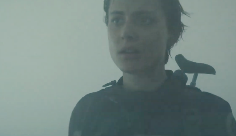 Blake (Nora Arnezeder) stands in a greenish haze on an alien planet called Earth. (Screenshot: Saban Films)