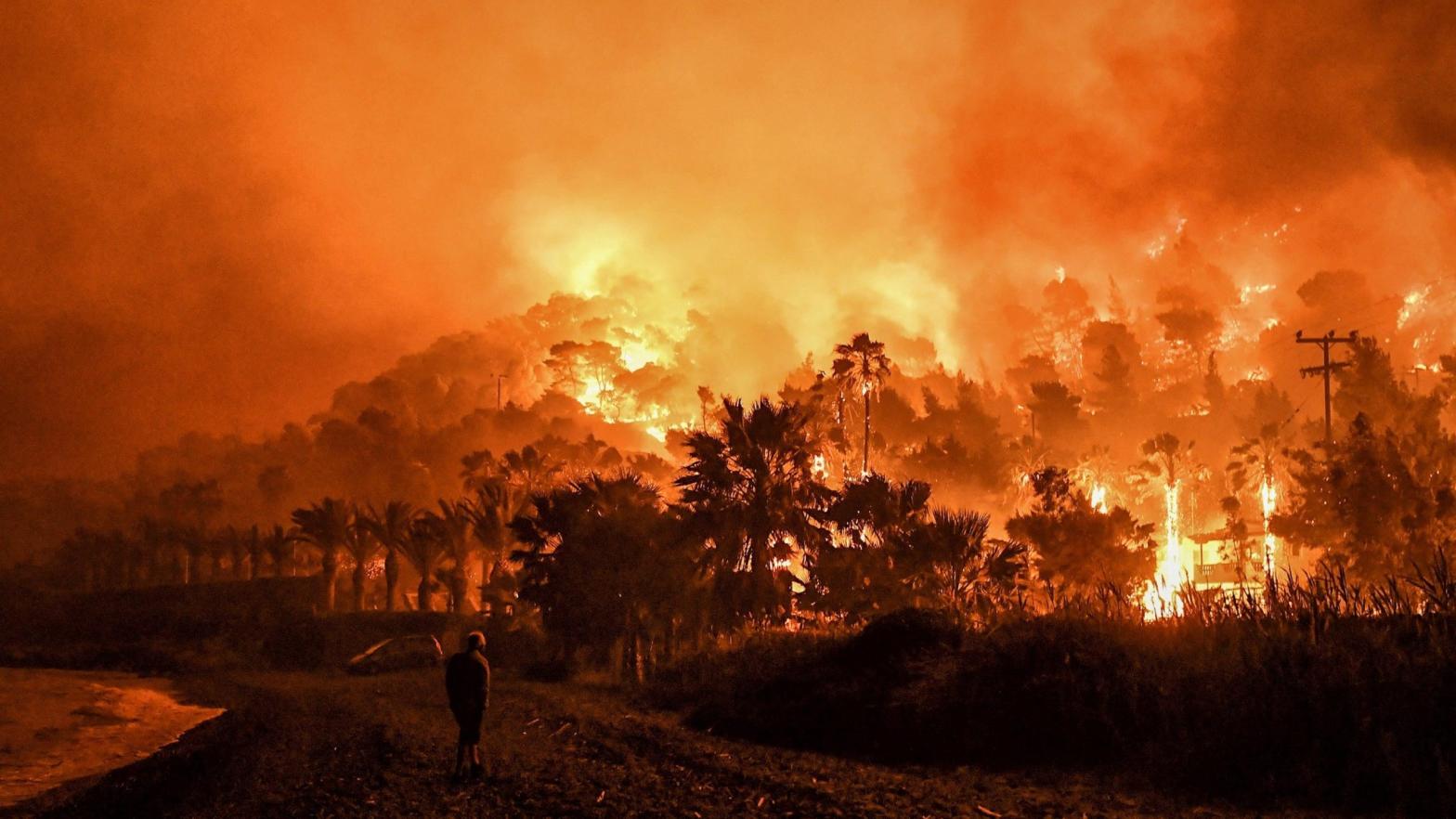A man stands in front of a wild fire in Schinos, west of Athens, on May 19, 2021. (Photo: Valerie Gache/AFP, Getty Images)