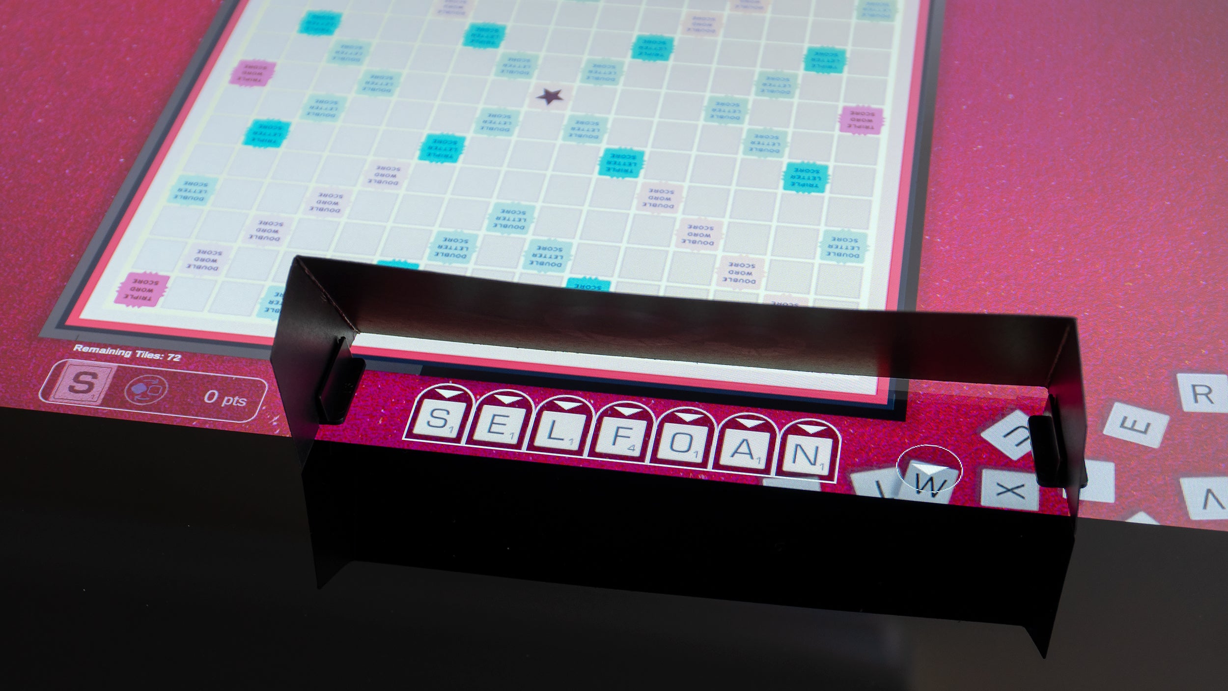 Some games don't translate to a giant touchscreen as well as others. Scrabble requires players to use a physical shield to keep their letter tiles hidden from other players. (Photo: Andrew Liszewski - Gizmodo)