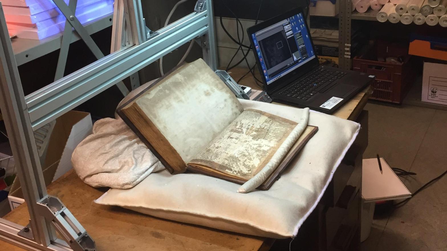 The book with the fragments getting multi-spectral scanning to enhance the faded ink. (Photo: Leah Tether)