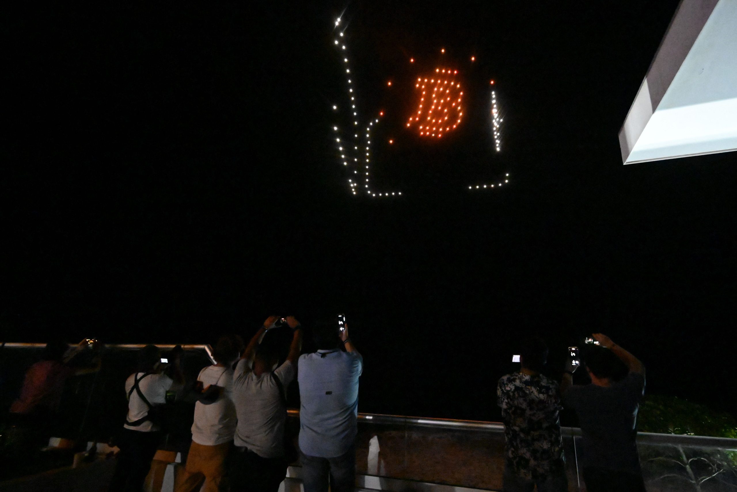 People take pictures as illuminated drones form figures inspired by the bitcoin logo at a reception hosted by American cryptocurrency developer and billionaire Brock Pierce on the first day of bitcoin's implementation as a currency in El Salvador, in El Sunzal Beach on September 7, 2021.  (Photo: Marvin Recinos/AFP, Getty Images)