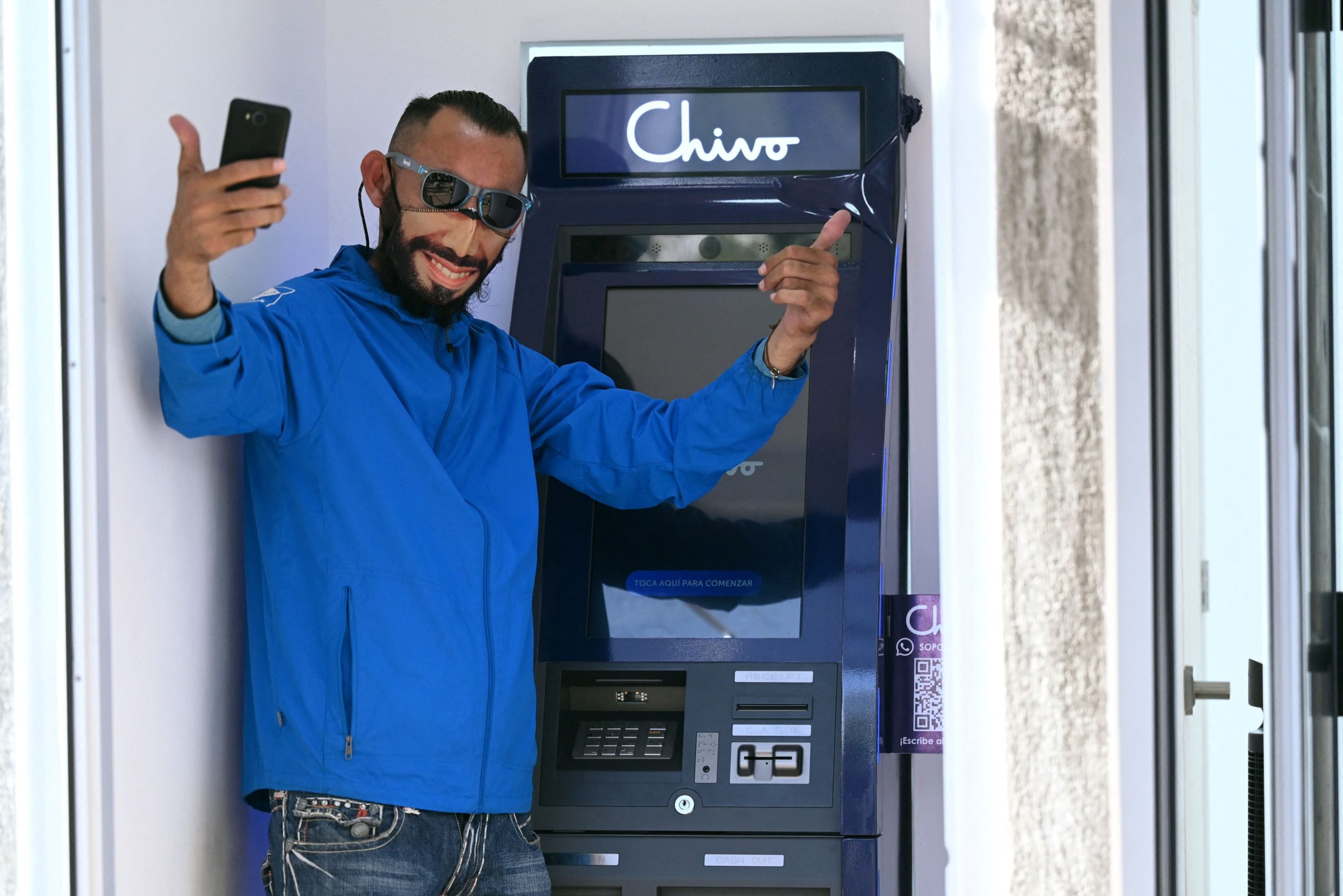 A man wearing a protective face mask with the image of Salvadoran  President Nayib Bukele pose for a picture at a bitcoin ATM in San  Salvador, on September 7, 2021. (Photo: Marvin Recinos/AFP, Getty Images)