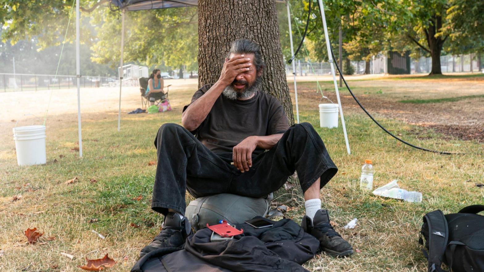 An unhoused man who asked to not be named tries to stay cool near a misting station in Lents Park during an extreme heat wave on Aug. 13, 2021 in Portland, Oregon. (Photo: Nathan Howard, Getty Images)