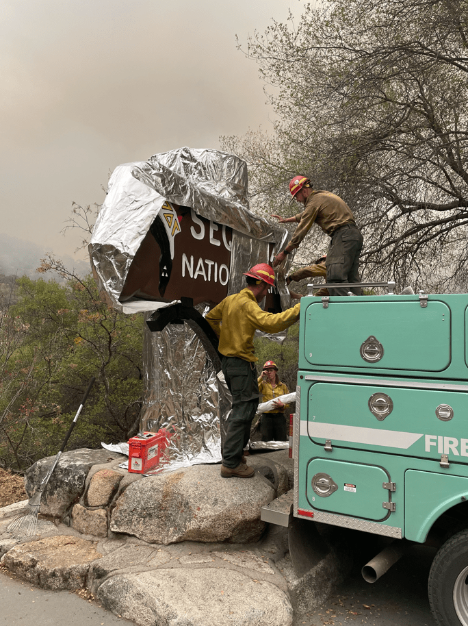 Firefighters wrap a historic Sequoia National Park sign in protective foil. (Photo: Inciweb/NPS)