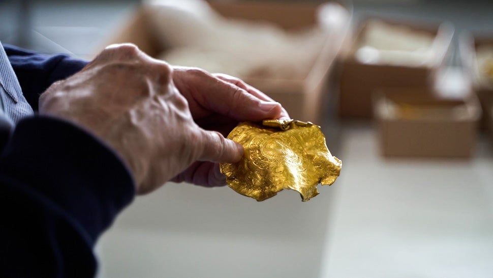 An investigator showing off one of the many items found in the gold hoard.  (Image: Vejle Museums)