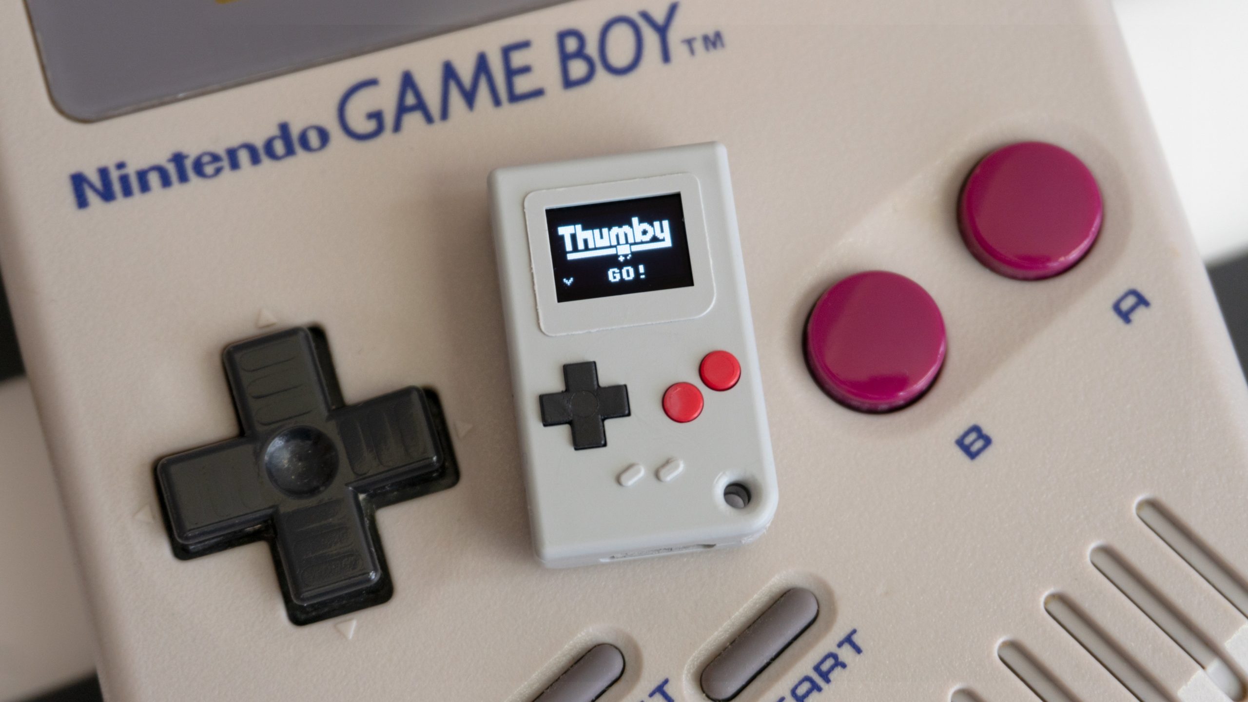 The original Game Boy looks enormous compared to the Thumby. (Photo: Andrew Liszewski - Gizmodo)