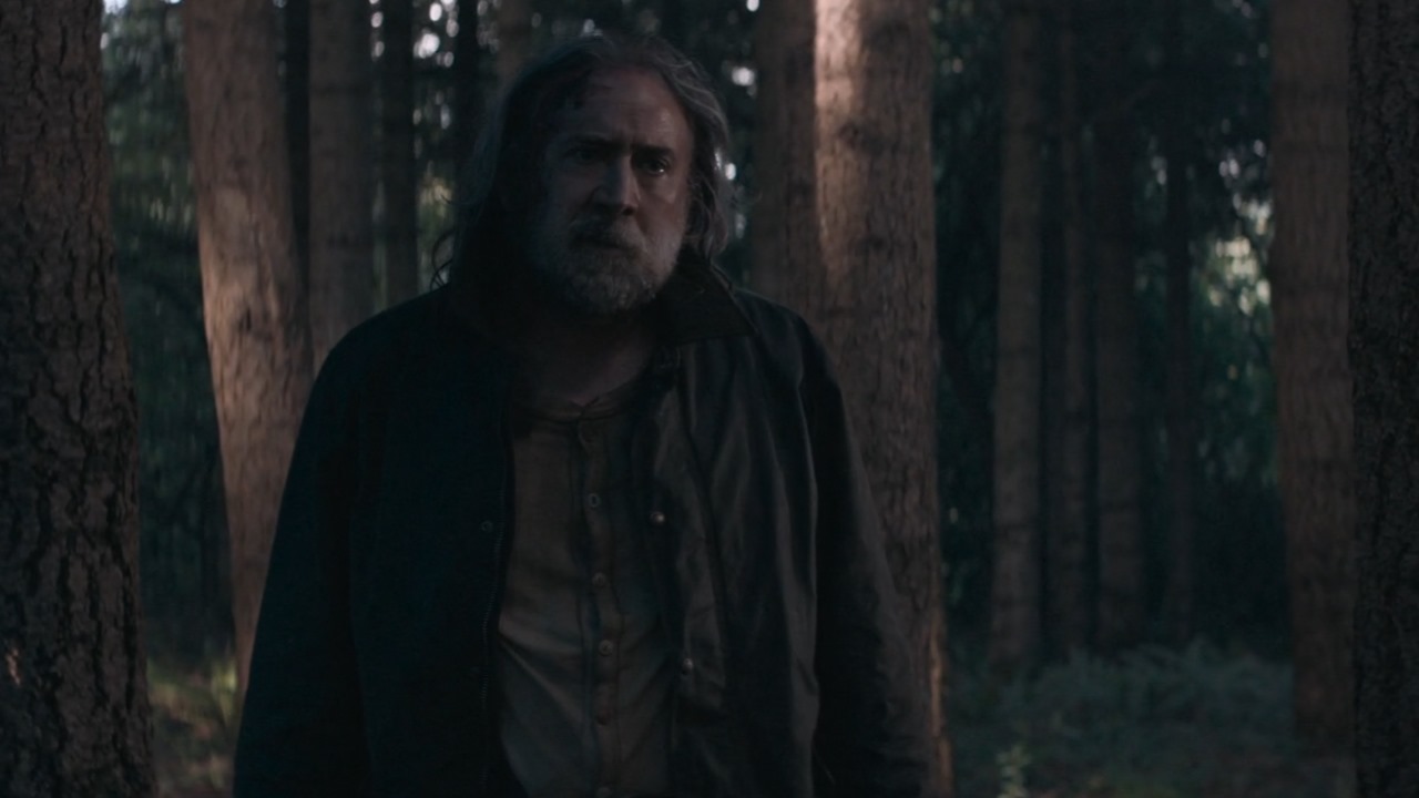 Nic Cage stands in the forest in old, weathered clothing
