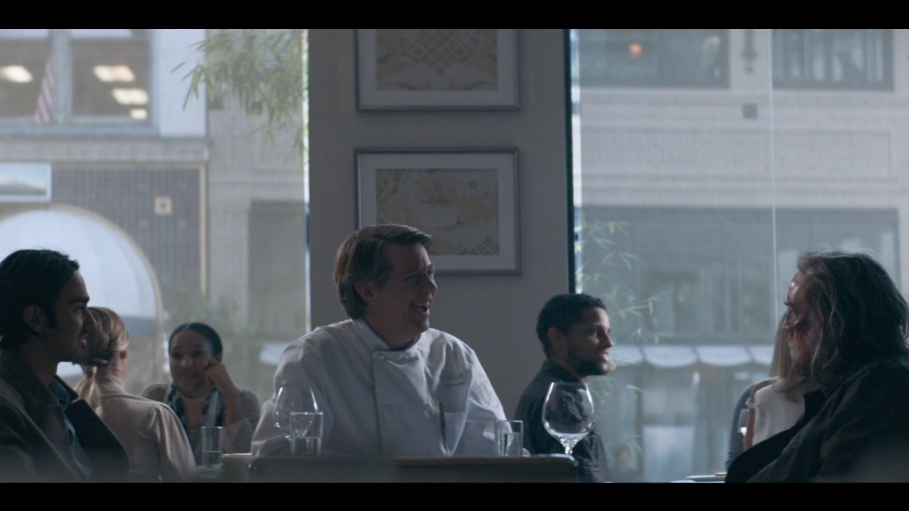 Pig Nic Cage talks to a nervously laughing chef while a younger man looks on