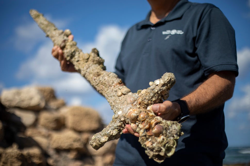Jacob Sharvit, director of the Marine Archaeology Unit of the Israel Antiquities Authority, holding the sword.  (Image: Ariel Schalit, AP)