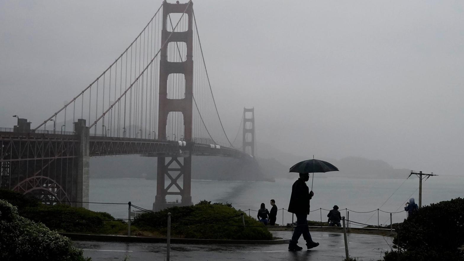 A pedestrian carries an umbrella while walking on a path in front of the Golden Gate Bridge in San Francisco on Wednesday, Oct. 20, 2021. (Photo: Jeff Chiu, AP)