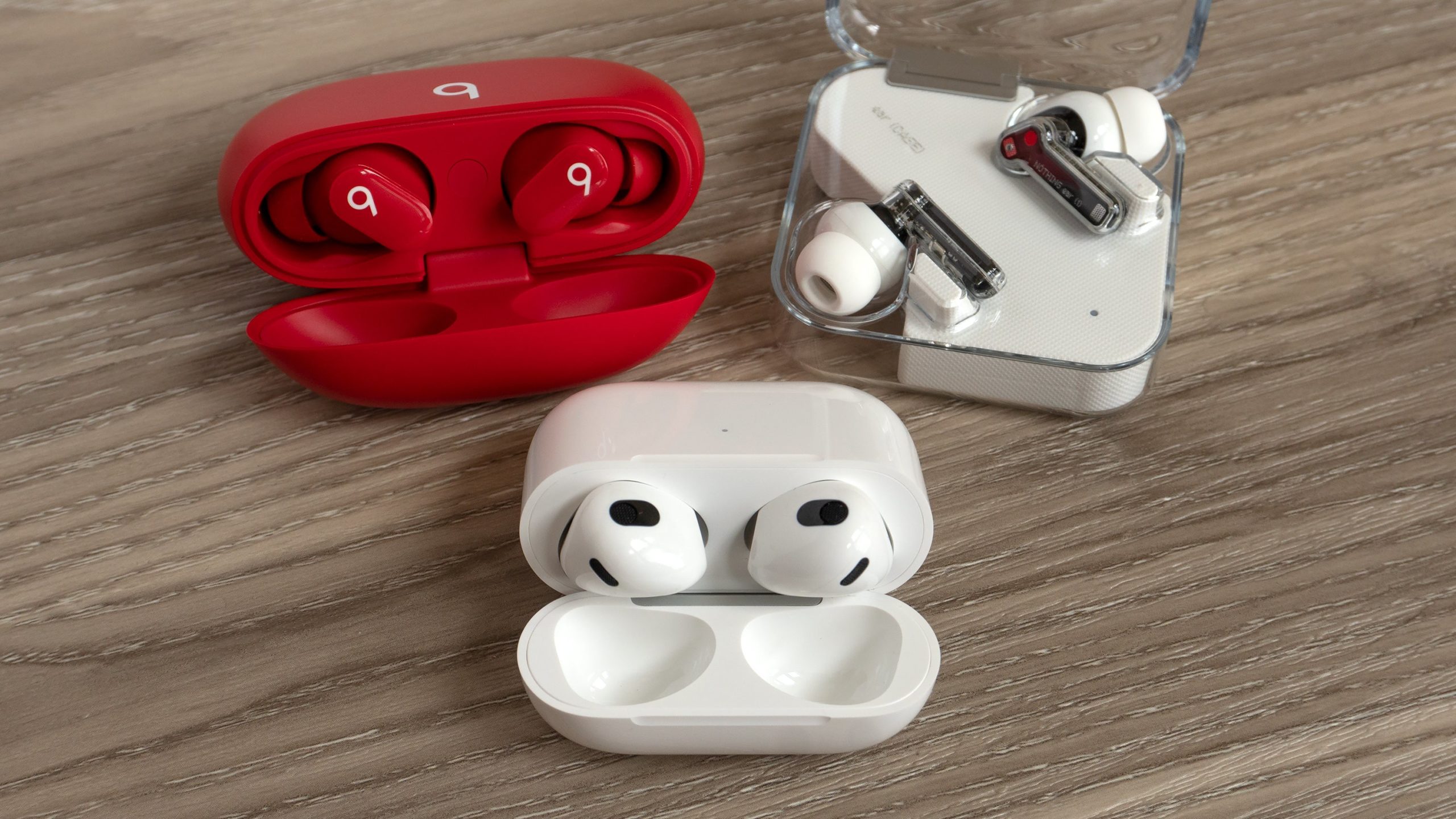 The third-gen AirPods (bottom) with the Beats Studio Buds (top left) and the Nothing Ear (1) (top right). (Photo: Andrew Liszewski - Gizmodo)