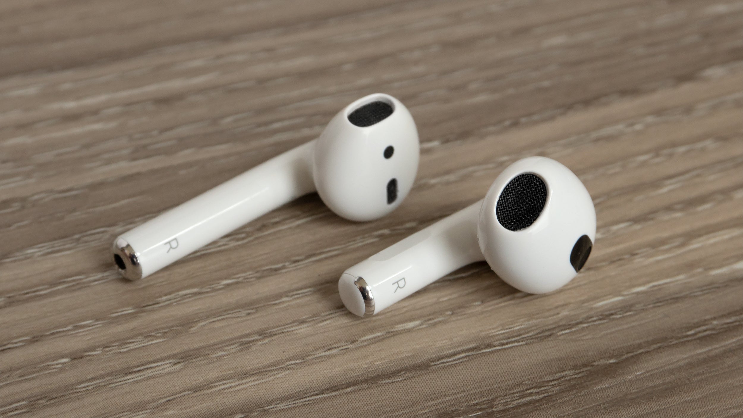 The new AirPods (right) have a more contoured design that also sits in the ear at a better angle than the second-gen AirPods (left) do. (Photo: Andrew Liszewski - Gizmodo)