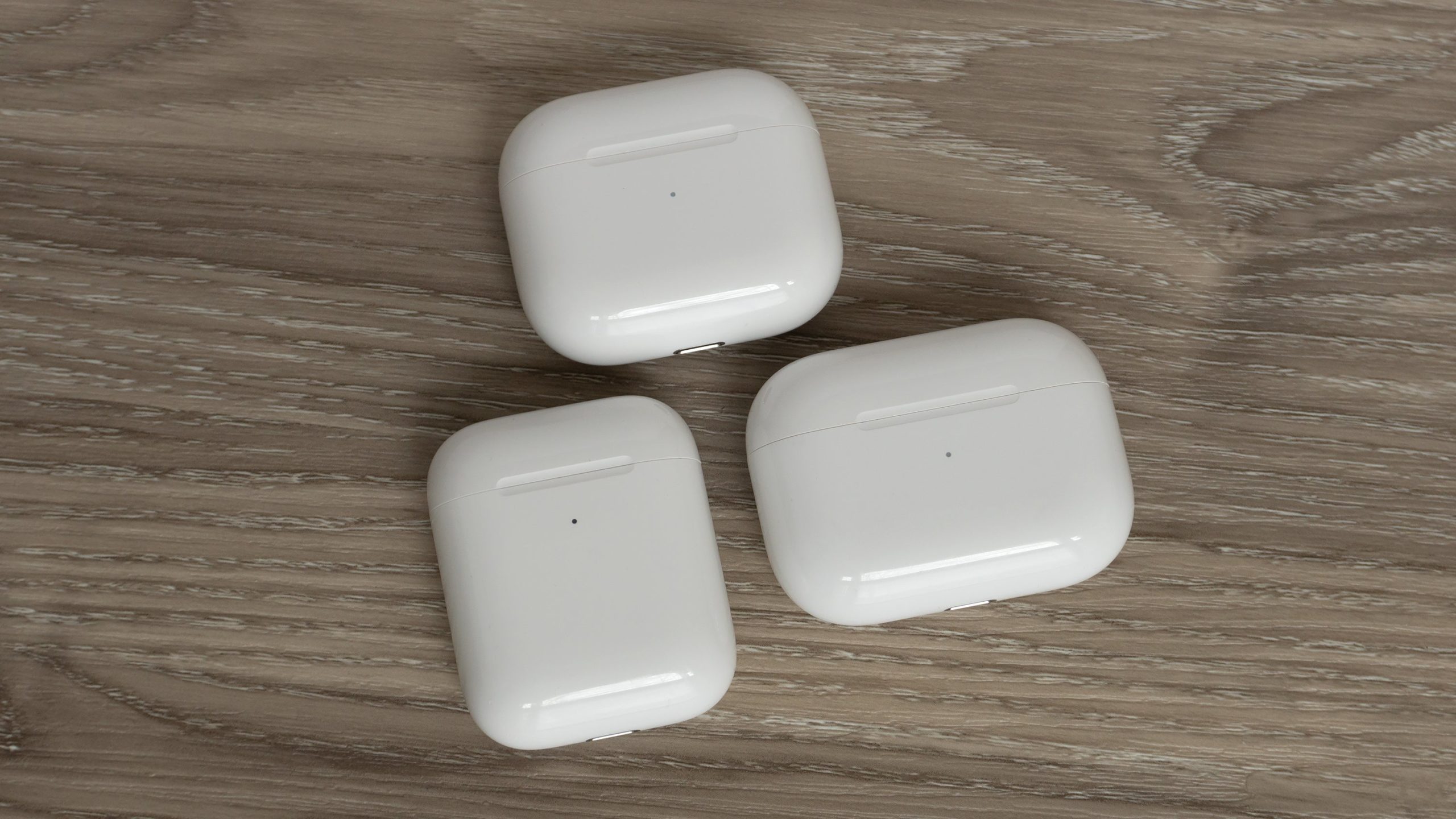 The third-gen AirPods charging case (top) compared to the second-gen charging case (bottom left) and the AirPods Pro charging case (bottom right). (Photo: Andrew Liszewski - Gizmodo)