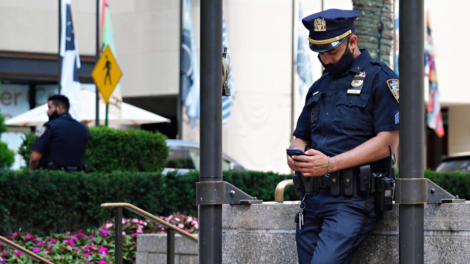 Officer chin-mask phones a friend. (Photo: Cindy Ord, Getty Images)