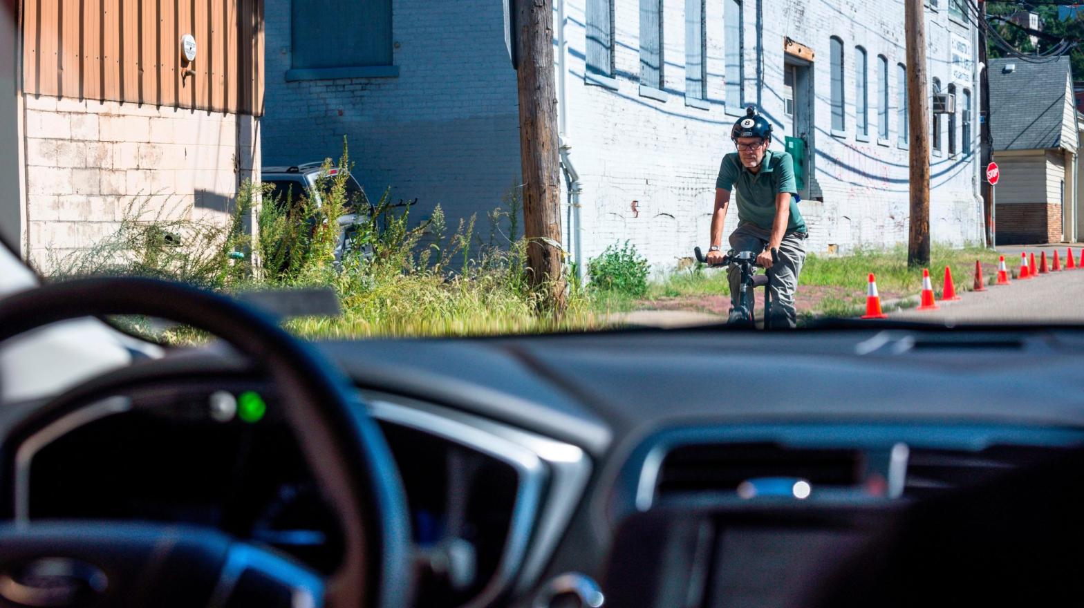 A bicyclist riding past an Uber self-driving car during a road test in Pittsburgh, Pennsylvania in 2016. (Photo: Angelo Merendino / AFP, Getty Images)