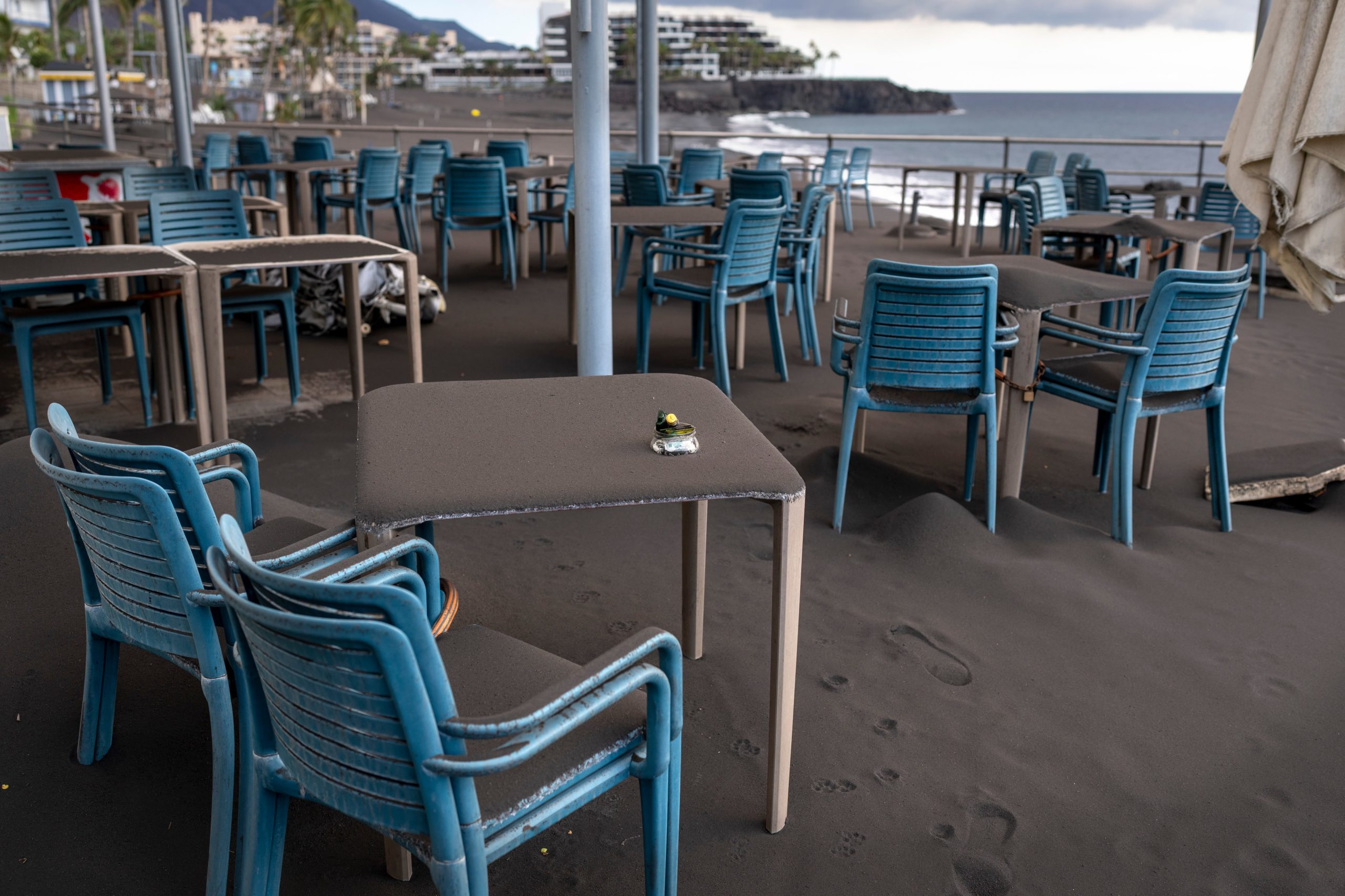 Ash covers tables and chairs on a bar terrace at the promenade of Puerto Naos village. (Photo: Emilio Morenatti, AP)