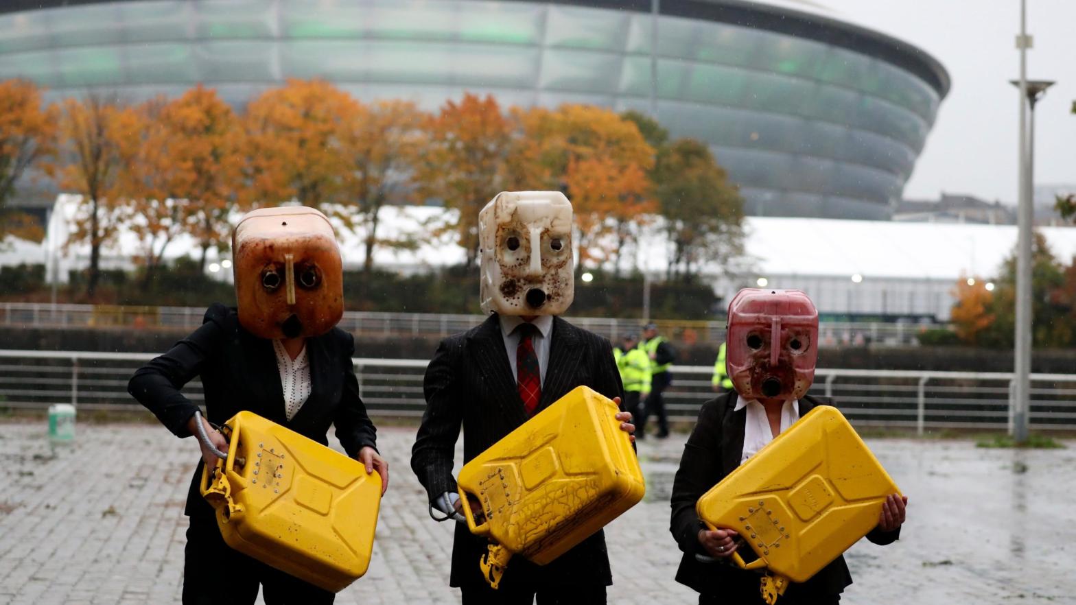 Activists hold jerrycans after spilling fake oil during their performance near the venue where the U.N. climate conference is being held in Glasgow, Scotland. (Photo: Scott Heppell, AP)