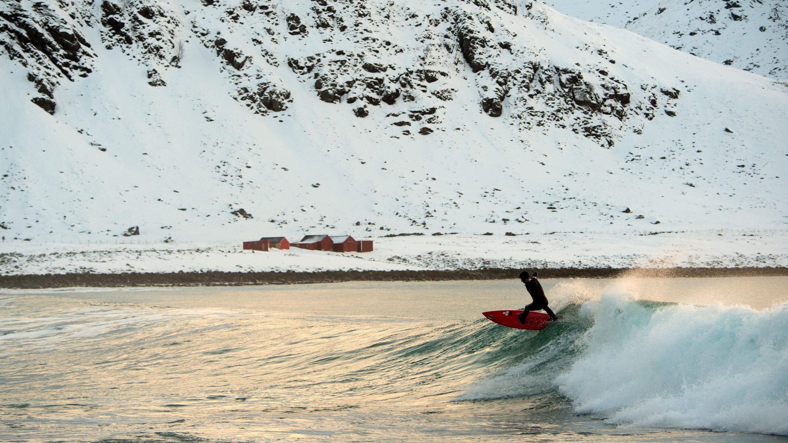 A surfer rides a wave at the snowy beach of Unstad, in Lofoten Island, Arctic Circle. (Photo: Olivier Morin/AFP, Getty Images)
