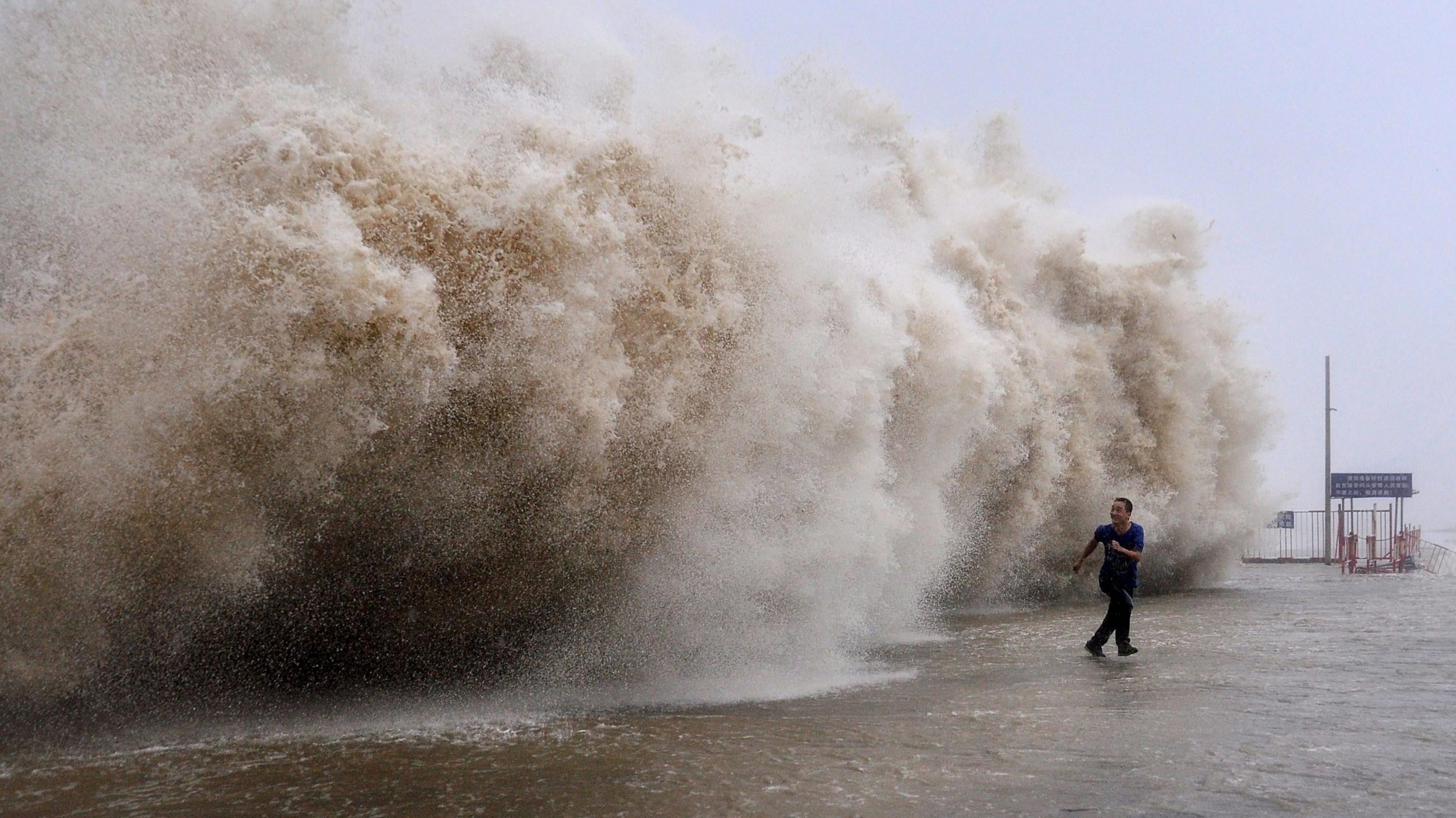 A man running away from a huge wave pushed up by Typhoon Usagi on a wharf in Shantou, China. (Photo: STR/AFP, Getty Images)