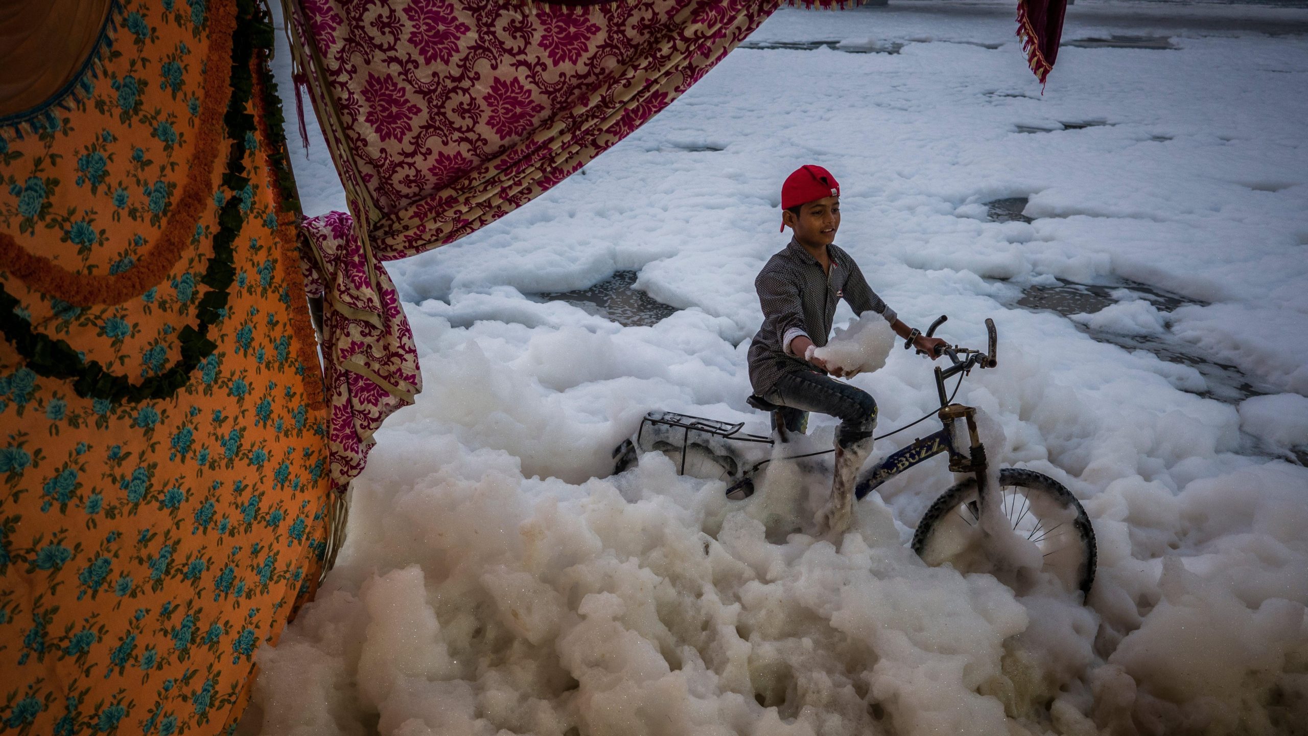  A child sits on a bicycle as he poses for a photograph taken by another child (unseen) at the banks of River Yamuna. (Photo: Anindito Mukherjee, Getty Images)
