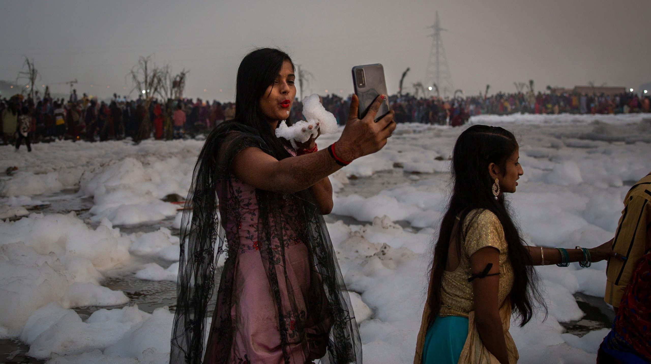 A woman takes a selfie while holding handful of chemical foam. (Photo: Altaf Qadri, AP)