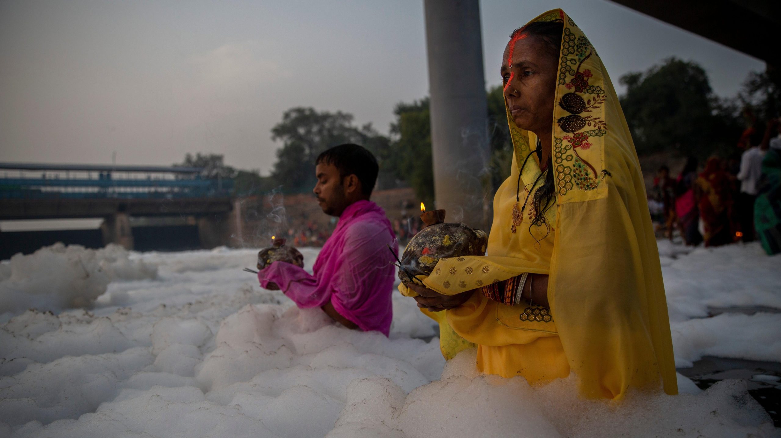 People perform rituals in Yamuna river, covered by chemical foam caused due to industrial and domestic pollution, during Chhath Puja festival. (Photo: Altaf Qadri, AP)