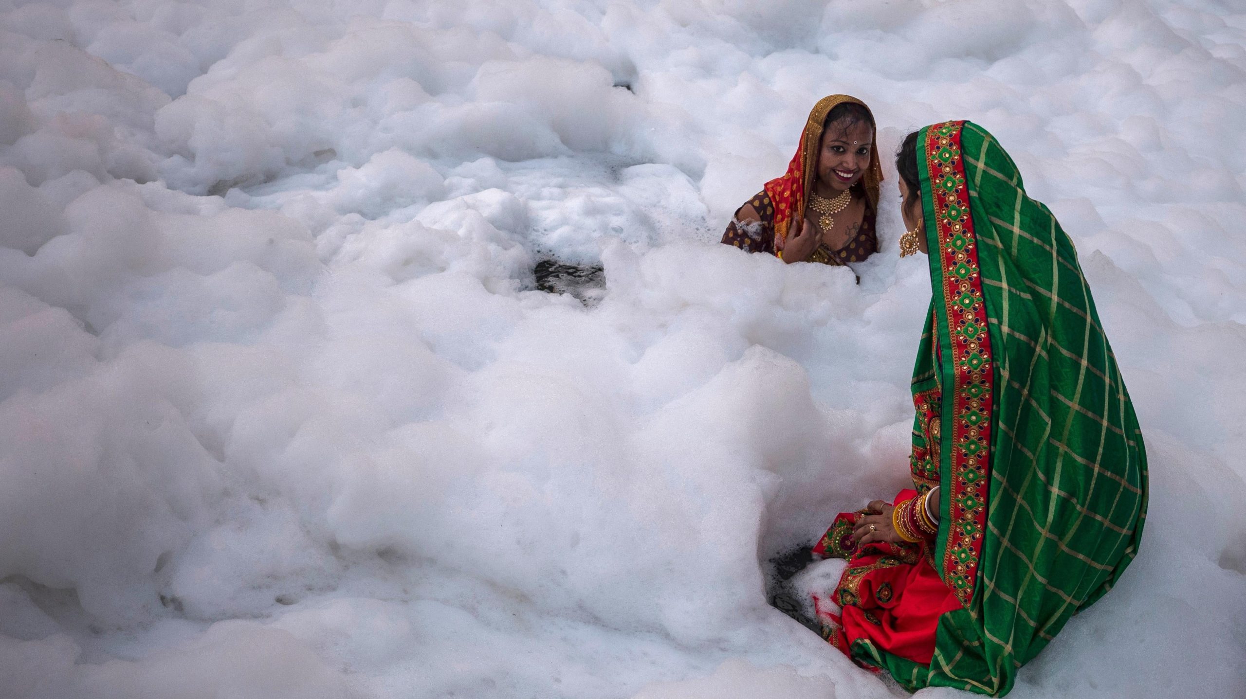 Women take a dip in the waters of River Yamuna amid toxic foam caused by pollution. (Photo: Anindito Mukherjee, Getty Images)