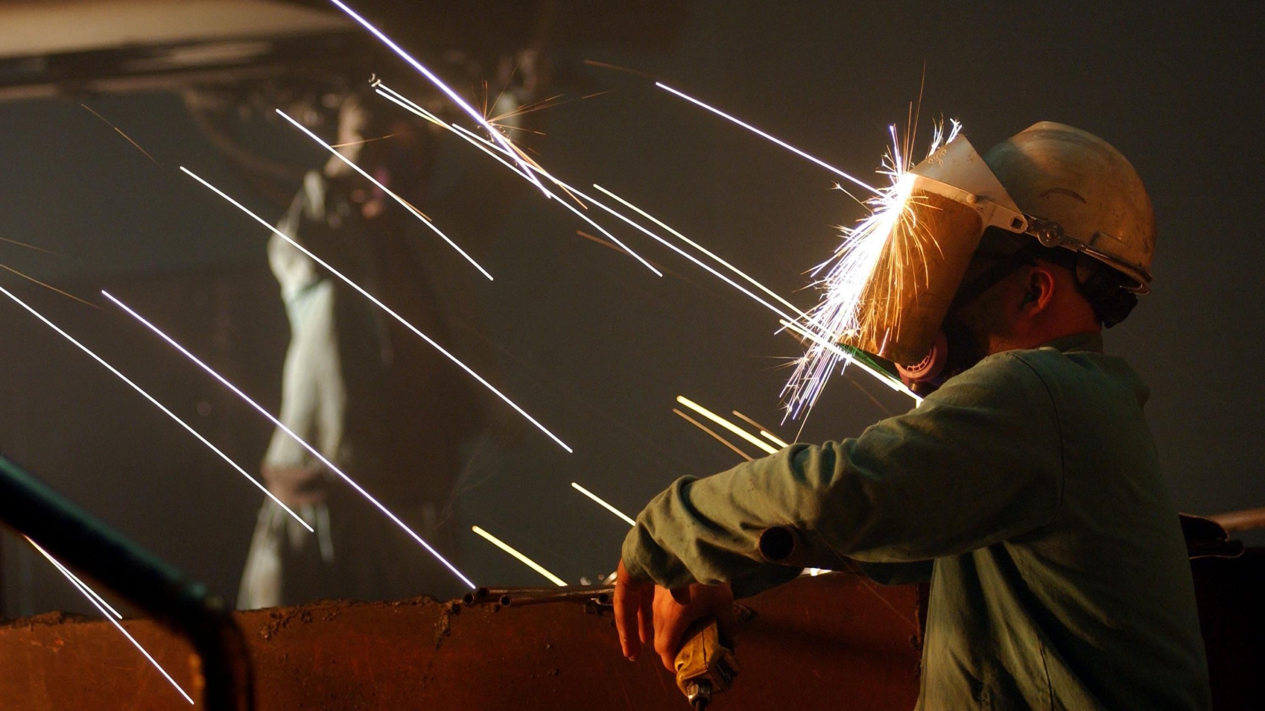 A worker is struck in the face with sparks from molten steel flowing into casts. (Photo: David McNew, Getty Images)