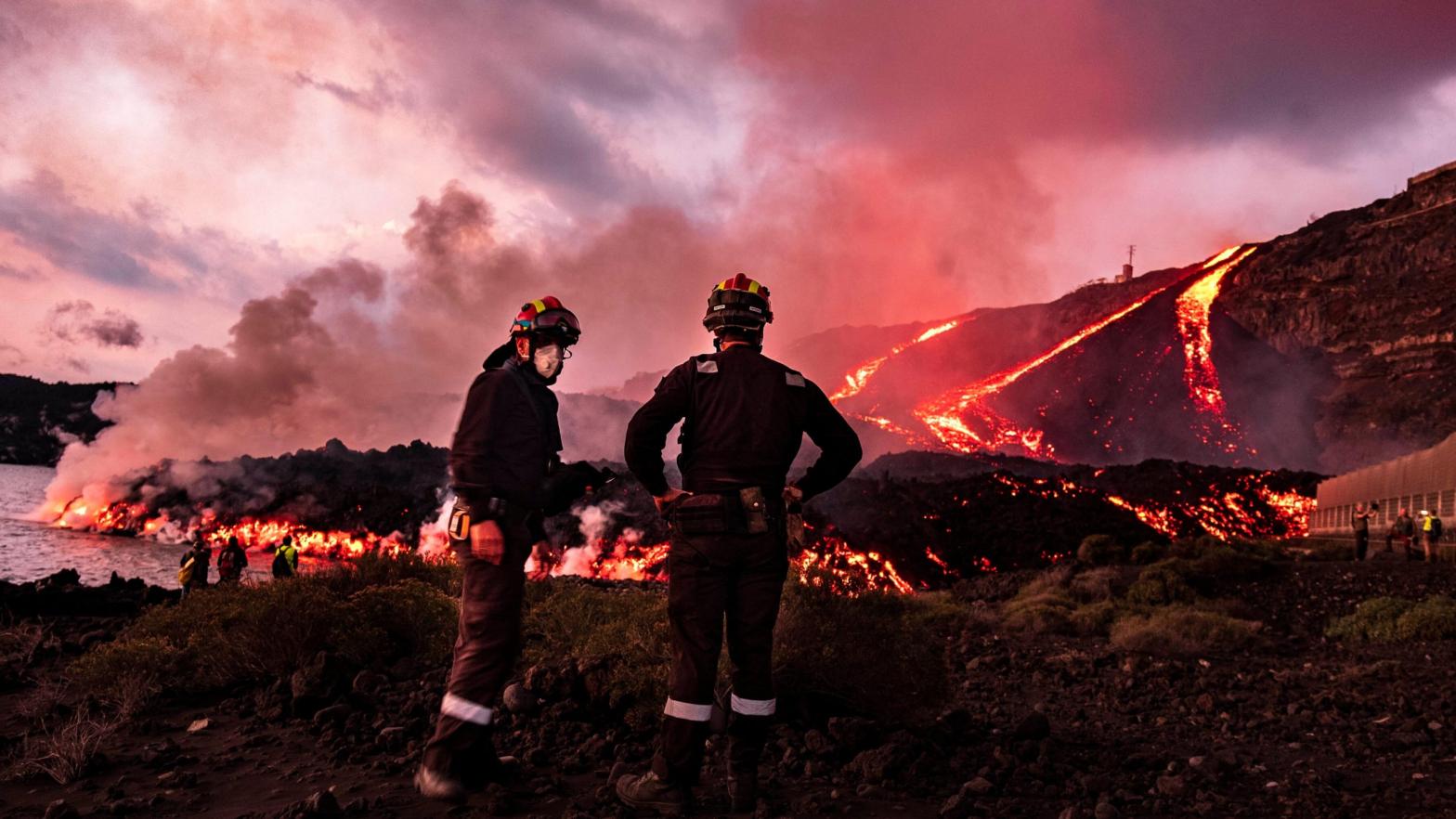 Members of a military emergency unit stand as lava flows from a volcano reaching the sea on the Canary island of La Palma, Spain. (Photo: Taner Orribo, AP)