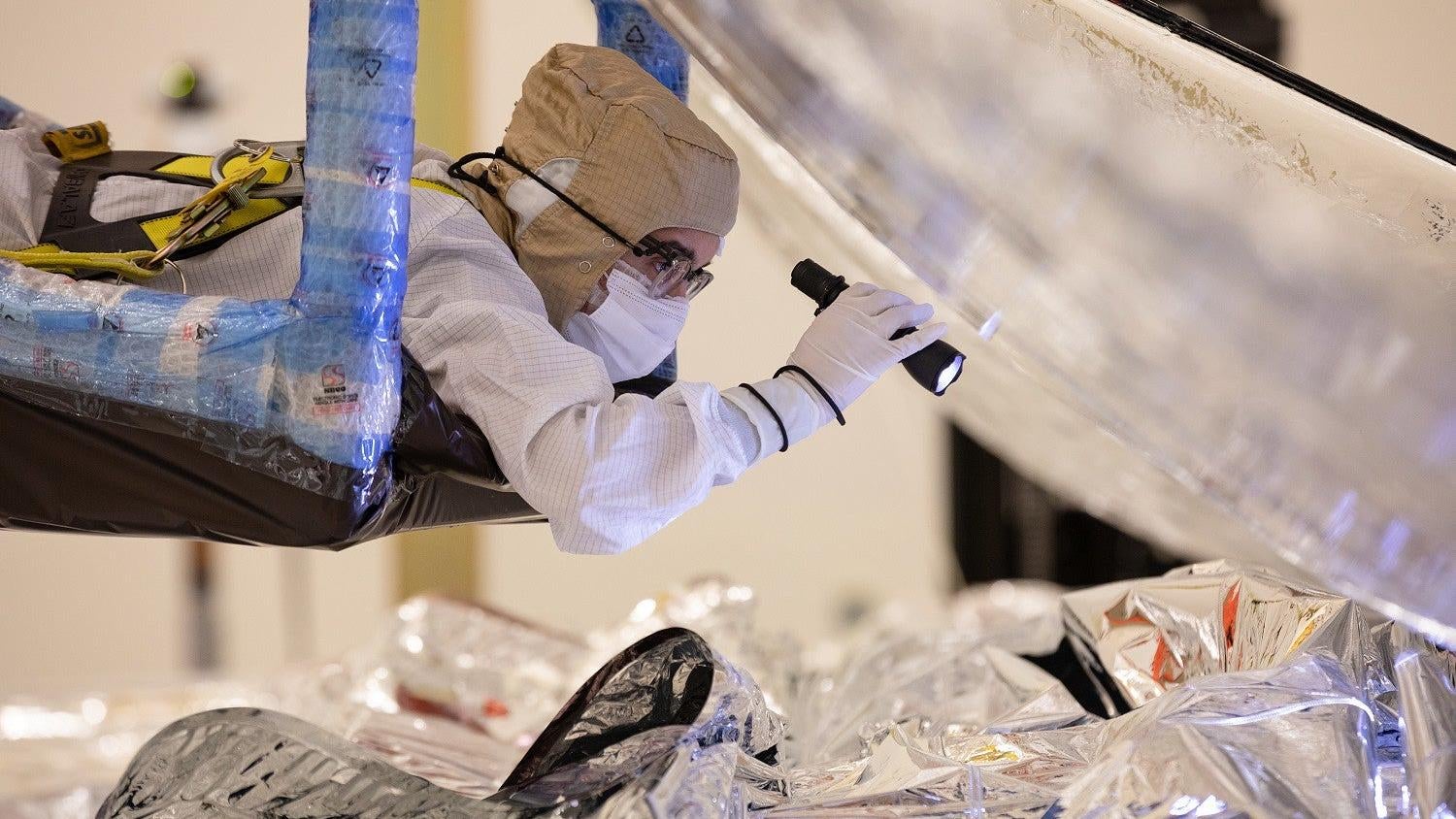 Archival image from February 2021, showing a Northrop Grumman technician inspecting the folding and packing of the Webb Space Telescope's sunshield.  (Photo: Northrop Grumman, Fair Use)