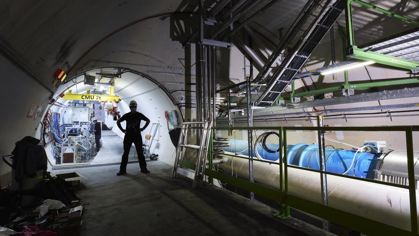 A worker stands in front of the FASER experiment at CERN. (Photo: CERN)
