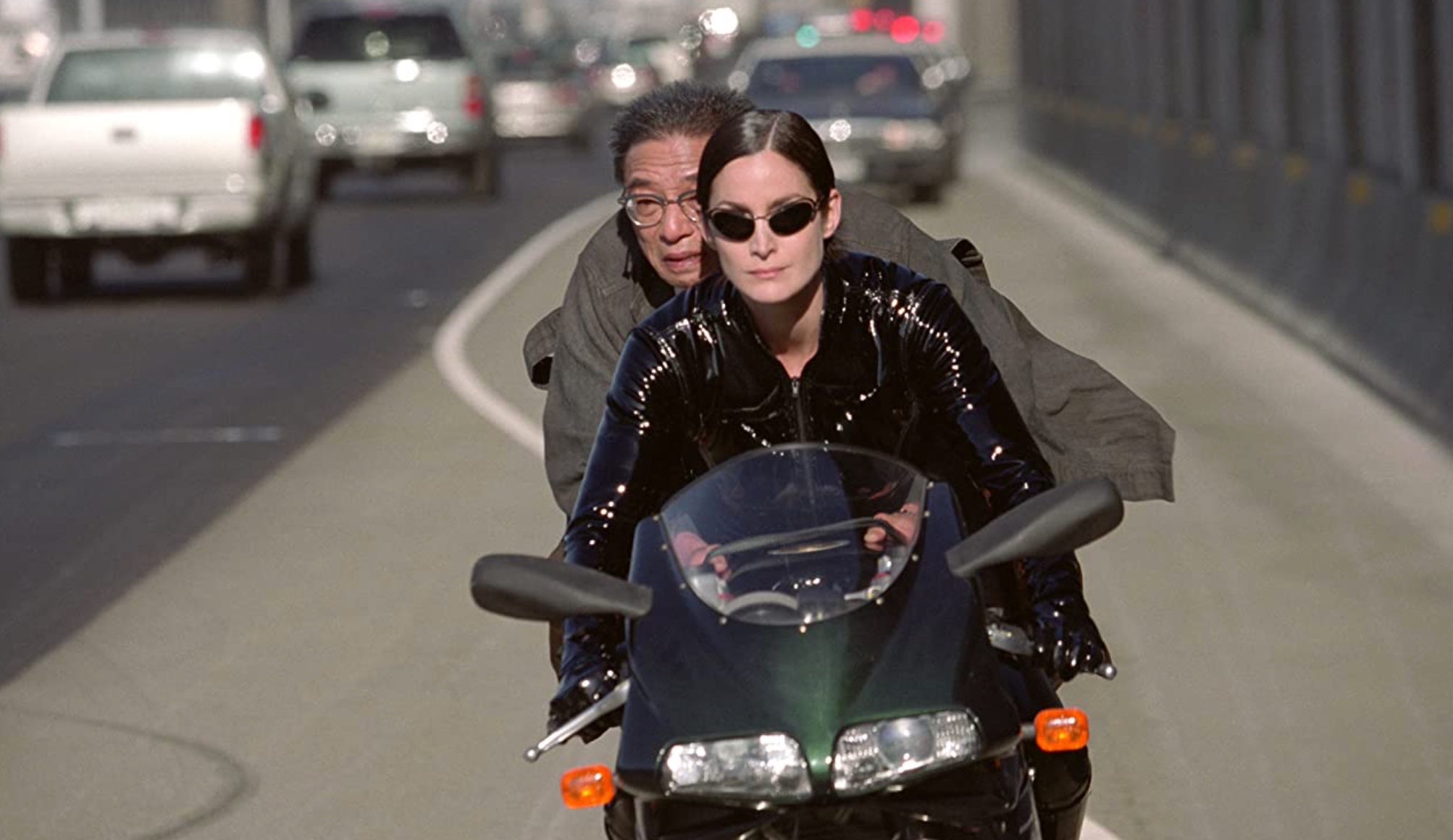 Trinity (Carrie-Anne Moss) and the Key Maker (Randall Duk Kim) riding down the highway. (Image: Warner Bros.)